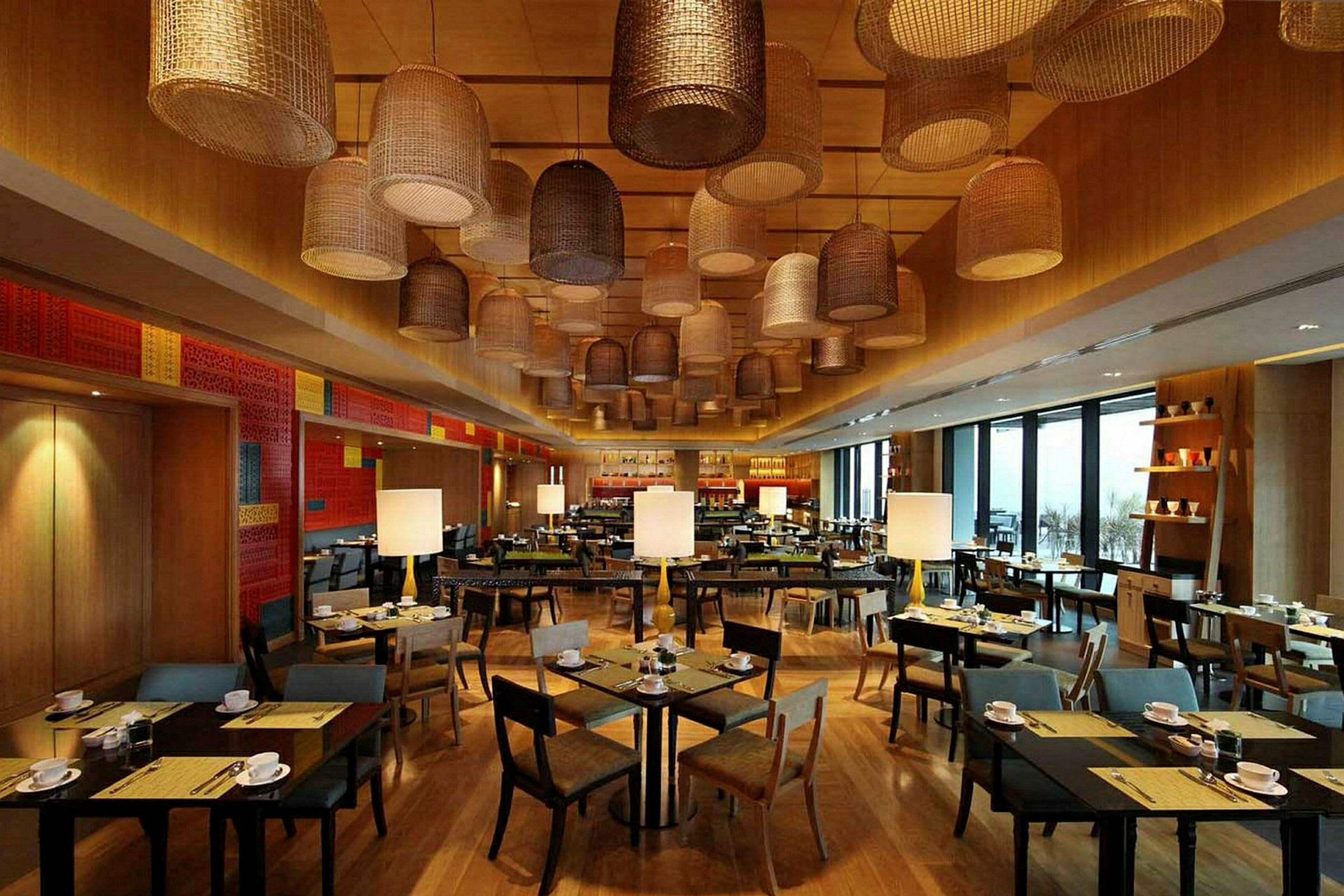 En restaurang med träinredning, moderna bord och stolar samt dekorativa taklampor av varierande design. (AI-genererad text)