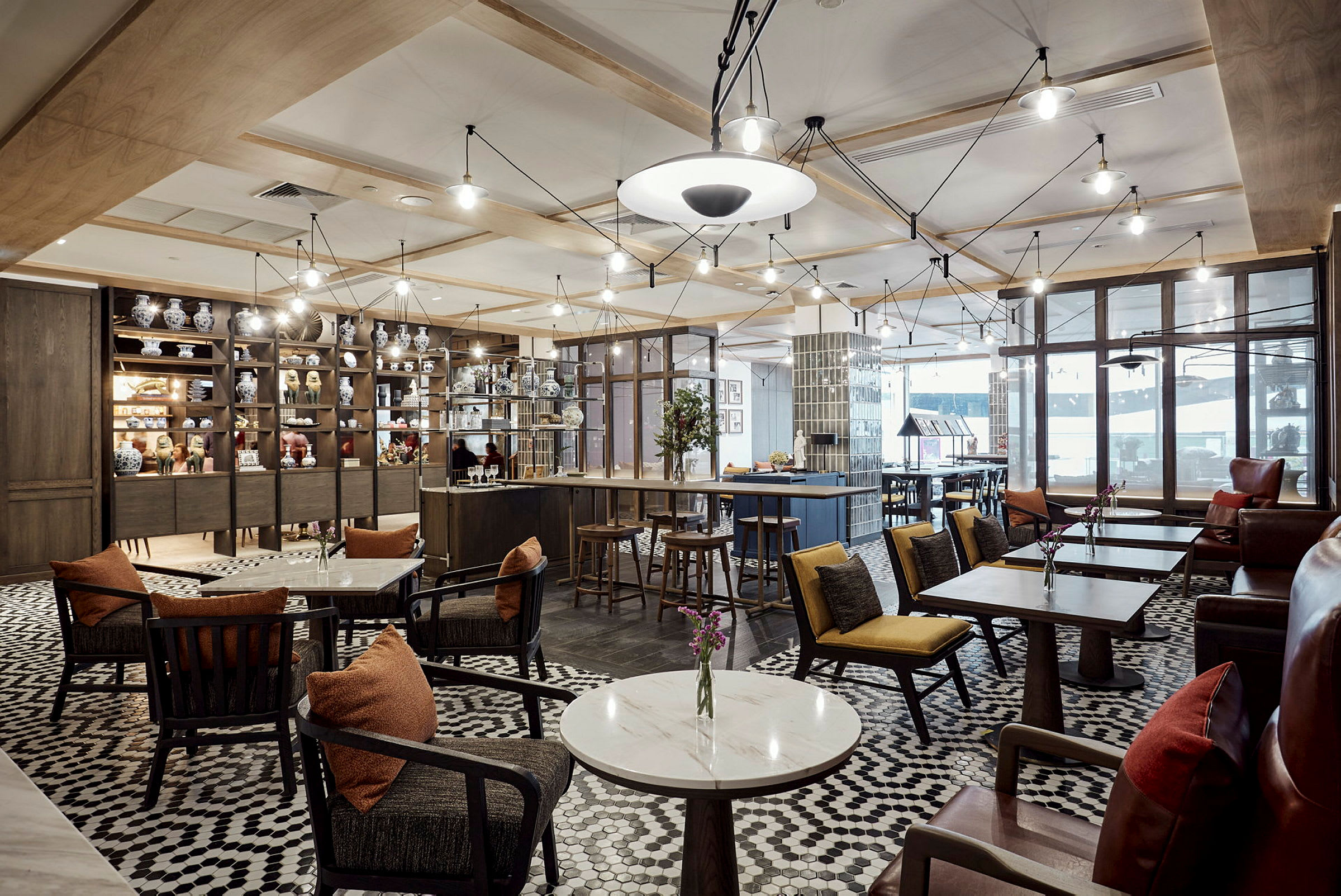 Ett elegant café med bord och stolar, omgivna av hyllor med porslinsprydnader. (AI-genererad text)