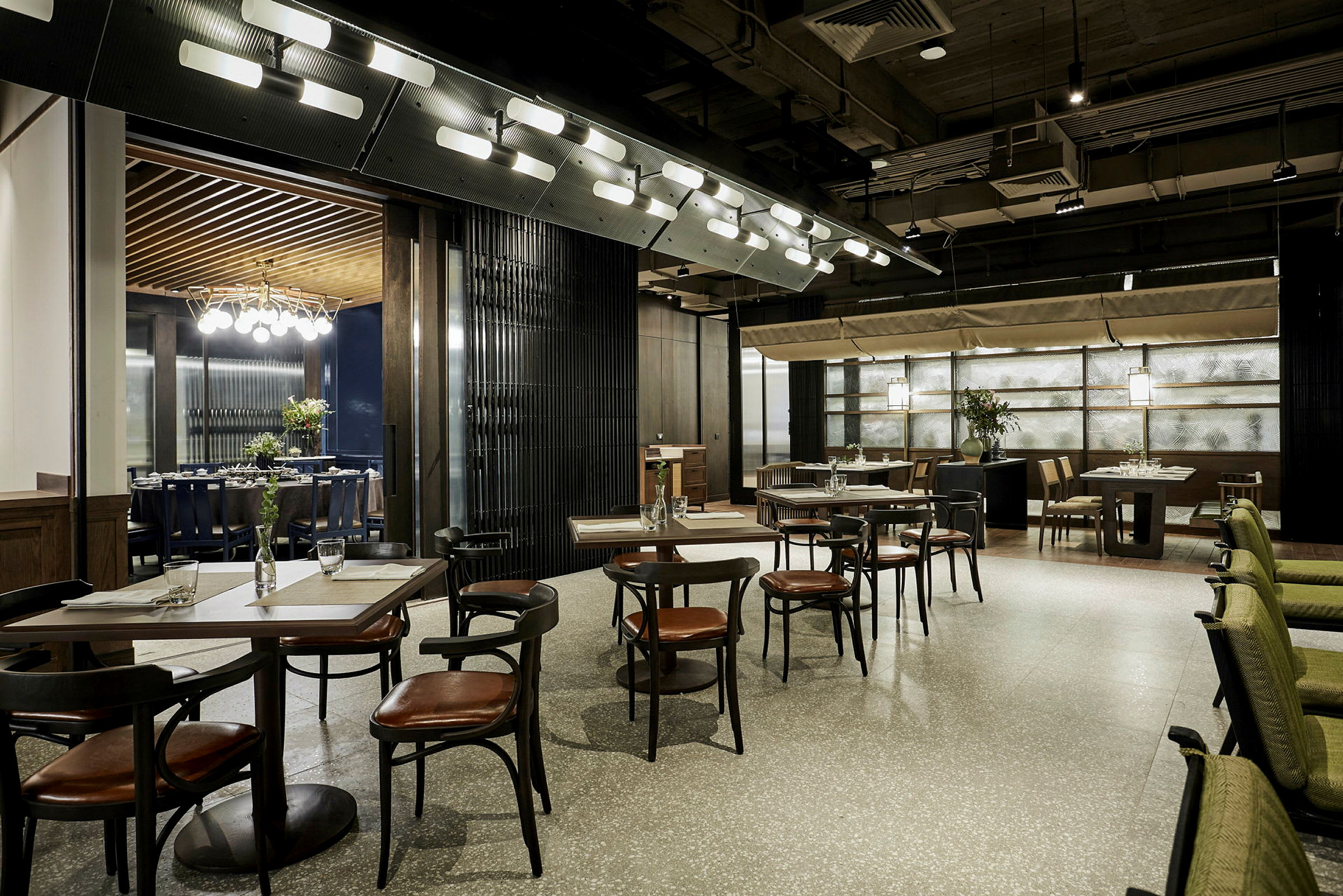 En modern och elegant restaurangmiljö med bord och stolar placerade i ett luftigt arrangemang. Designen inkluderar stilrena detaljer och mjuk belysning. (AI-genererad text)