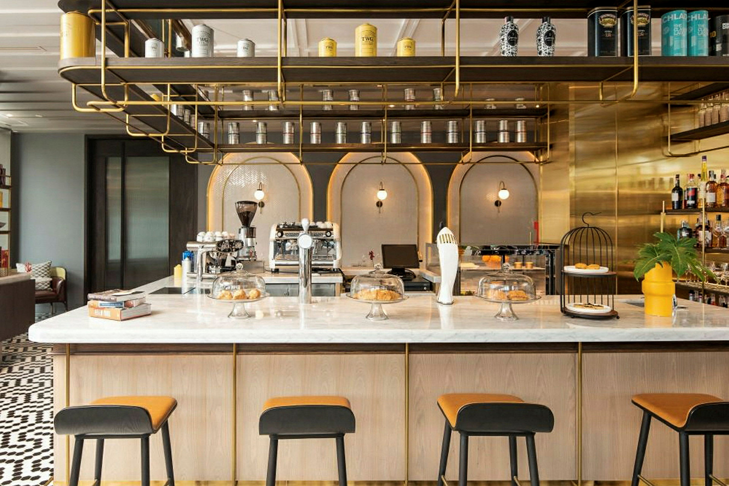 Ett elegant kafé med modern inredning, en marmorbar, höga stolar och hyllor dekorerade med burkar och flaskor. (AI-genererad text)