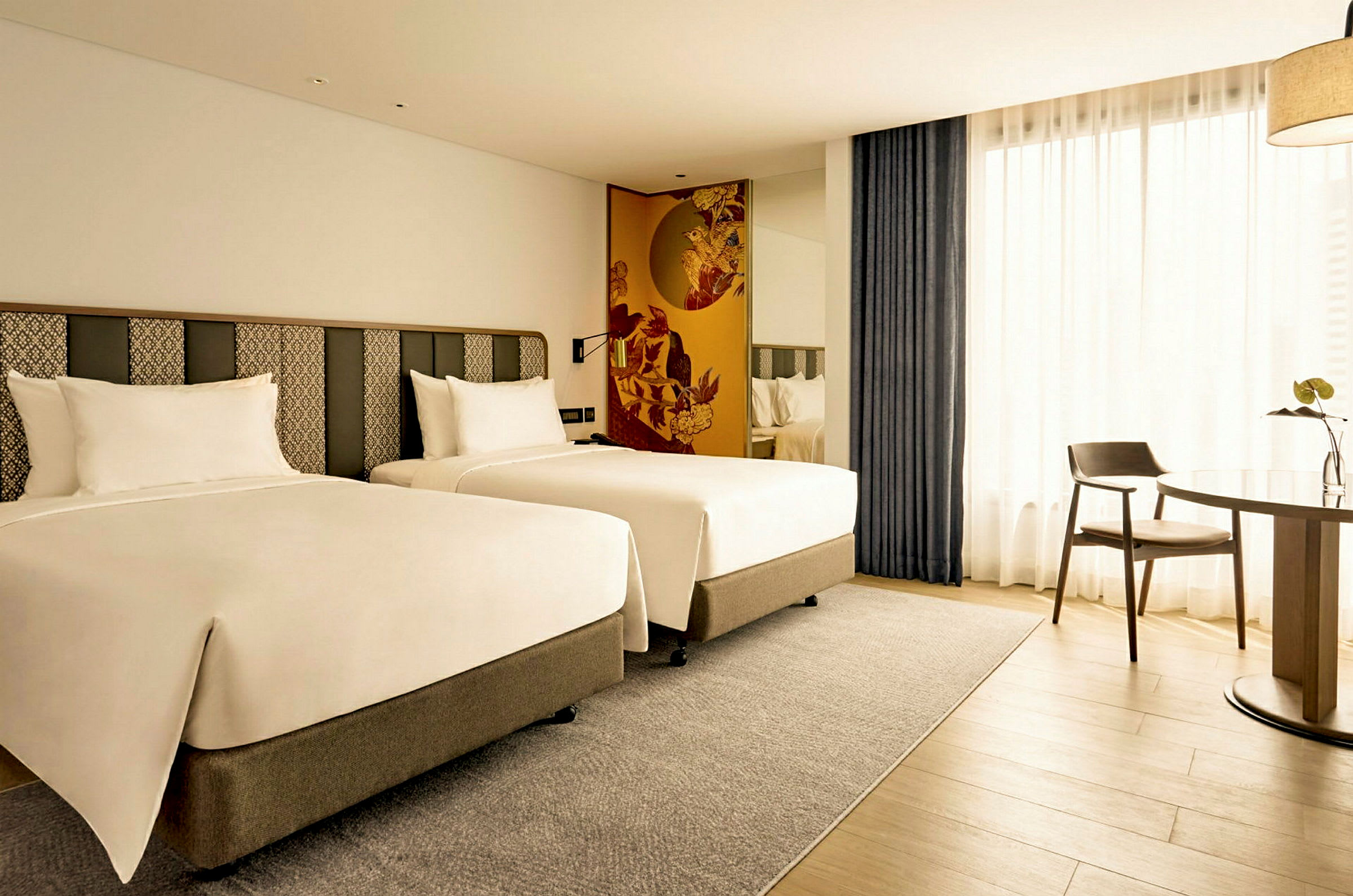 Hotellrum med två enkelsängar och ett bord med en stol. (AI-genererad text)
