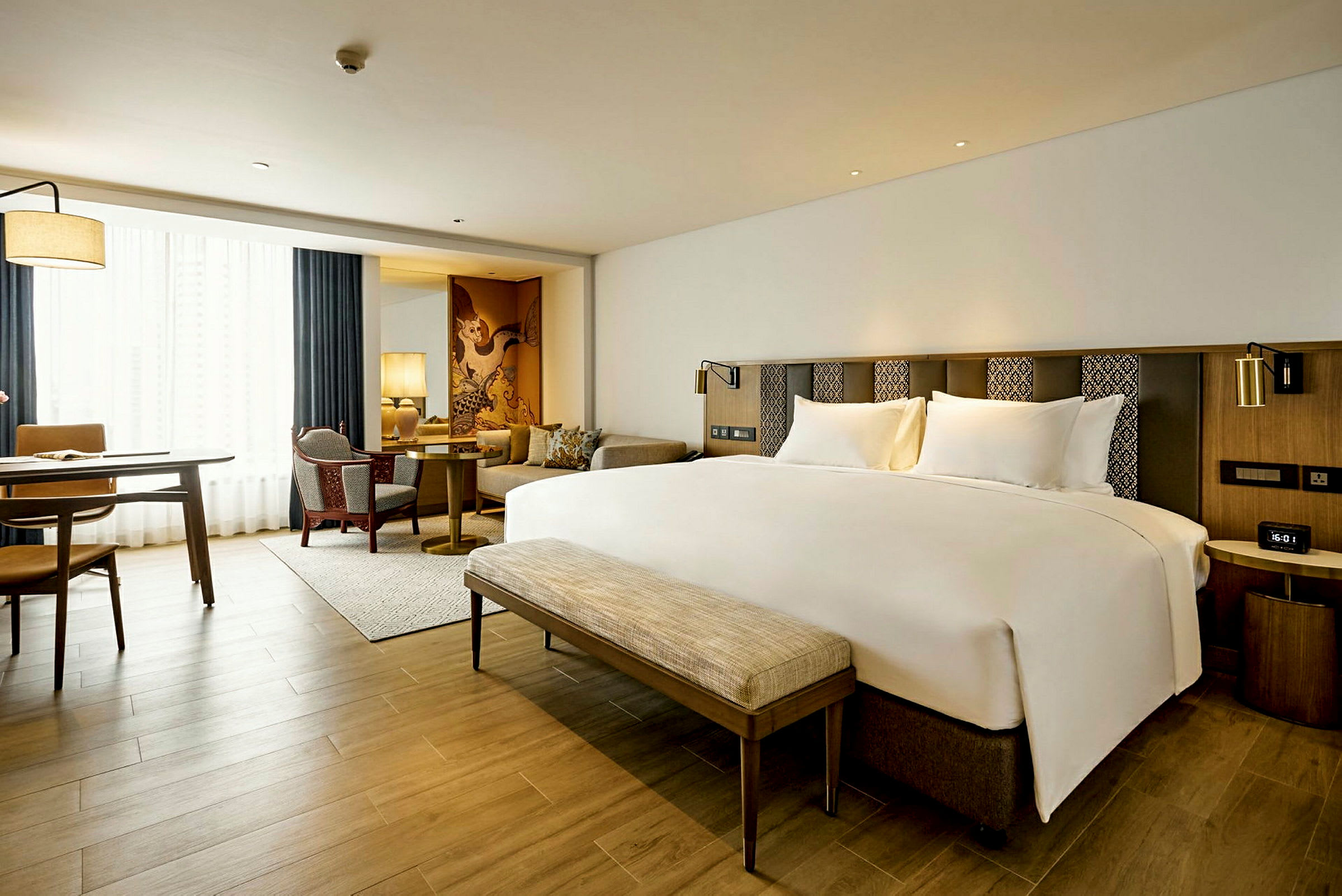 Modernt hotellrum med en stor säng, sittgrupp och arbetsbord. (AI-genererad text)
