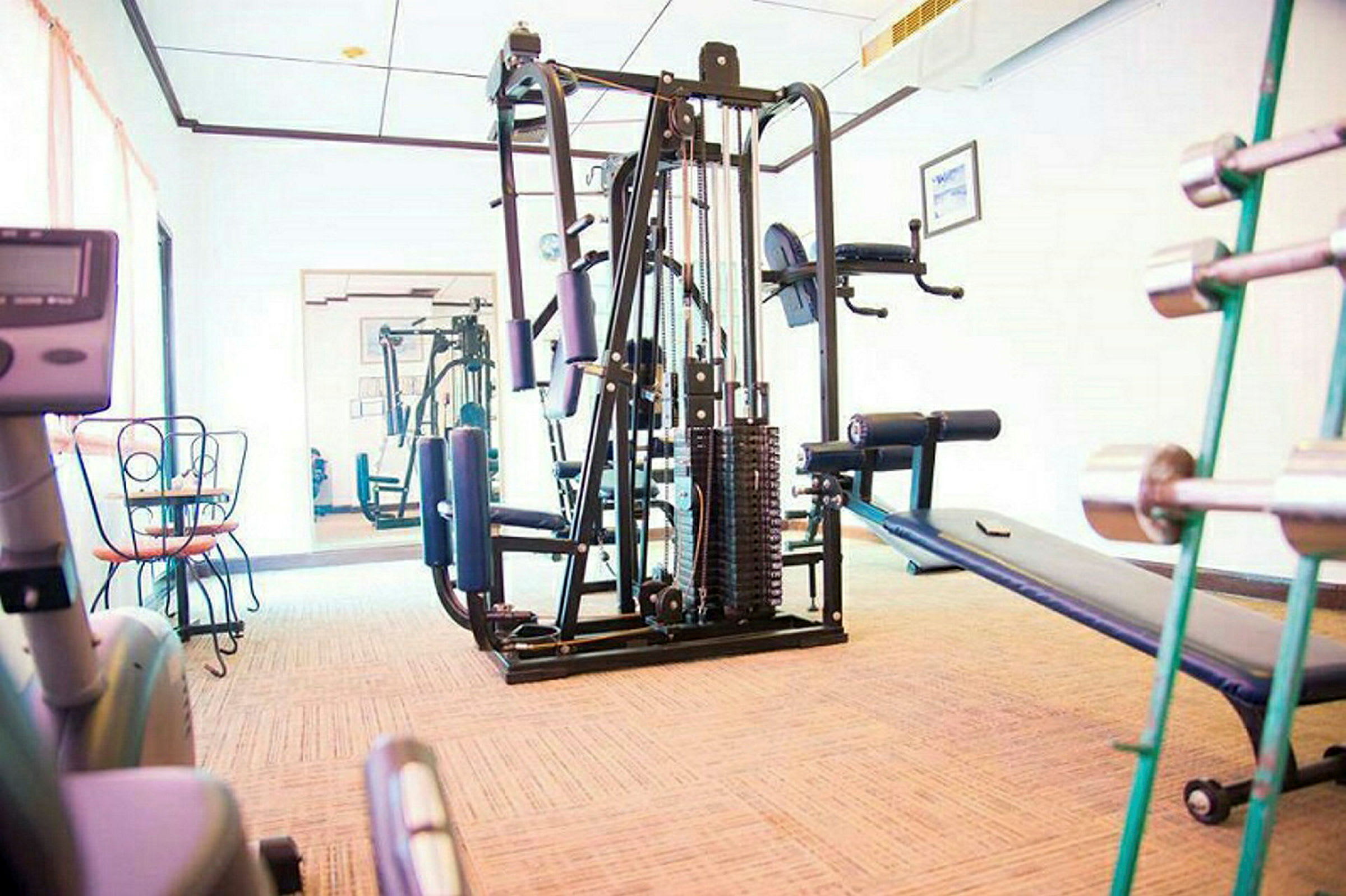 Ett gym med träningsutrustning som en multistation, hantlar och en träningsbänk. (AI-genererad text)