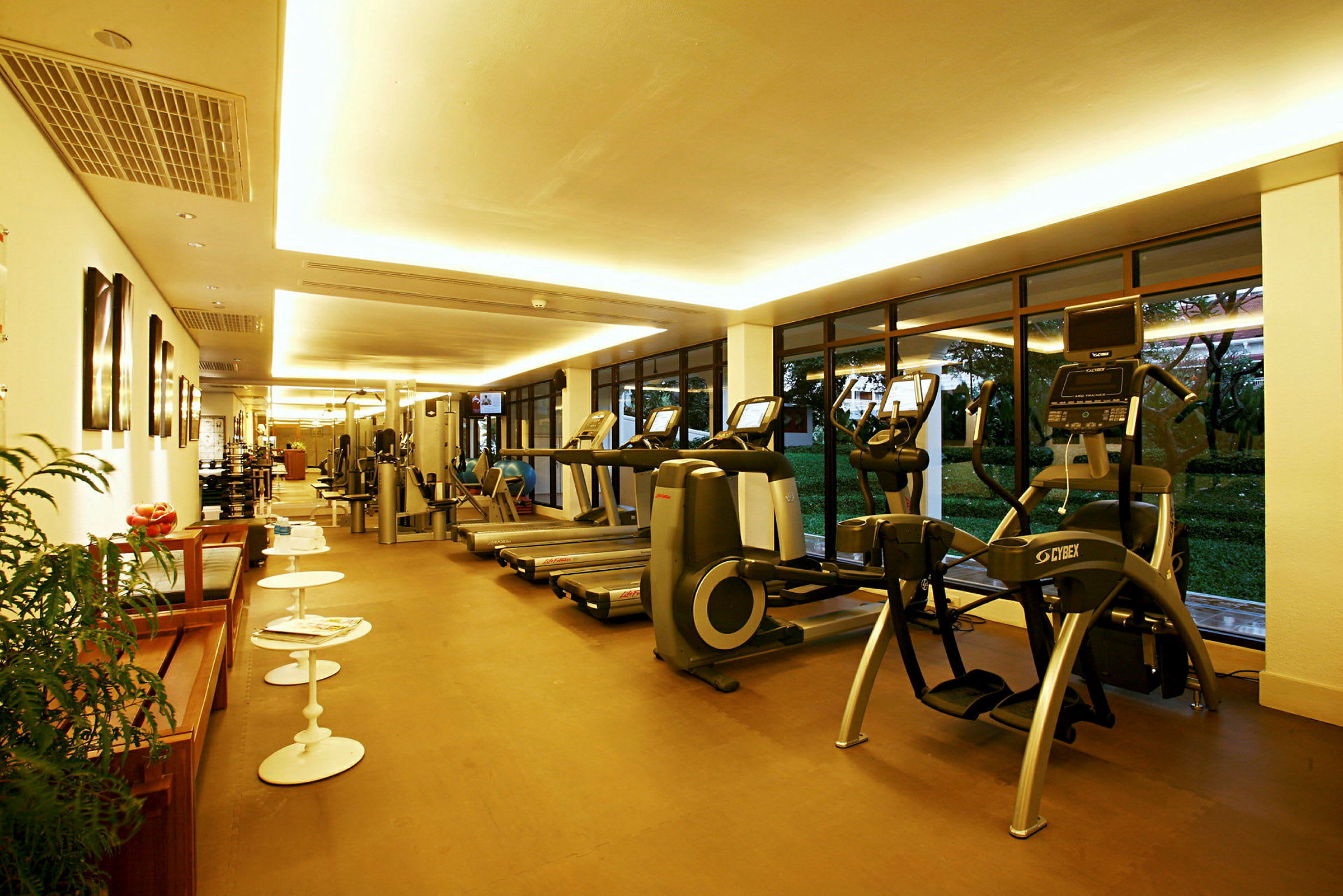 Ett modernt gym med träningsmaskiner och löpband inomhus, med stora fönster och ljus belysning. (AI-genererad text)