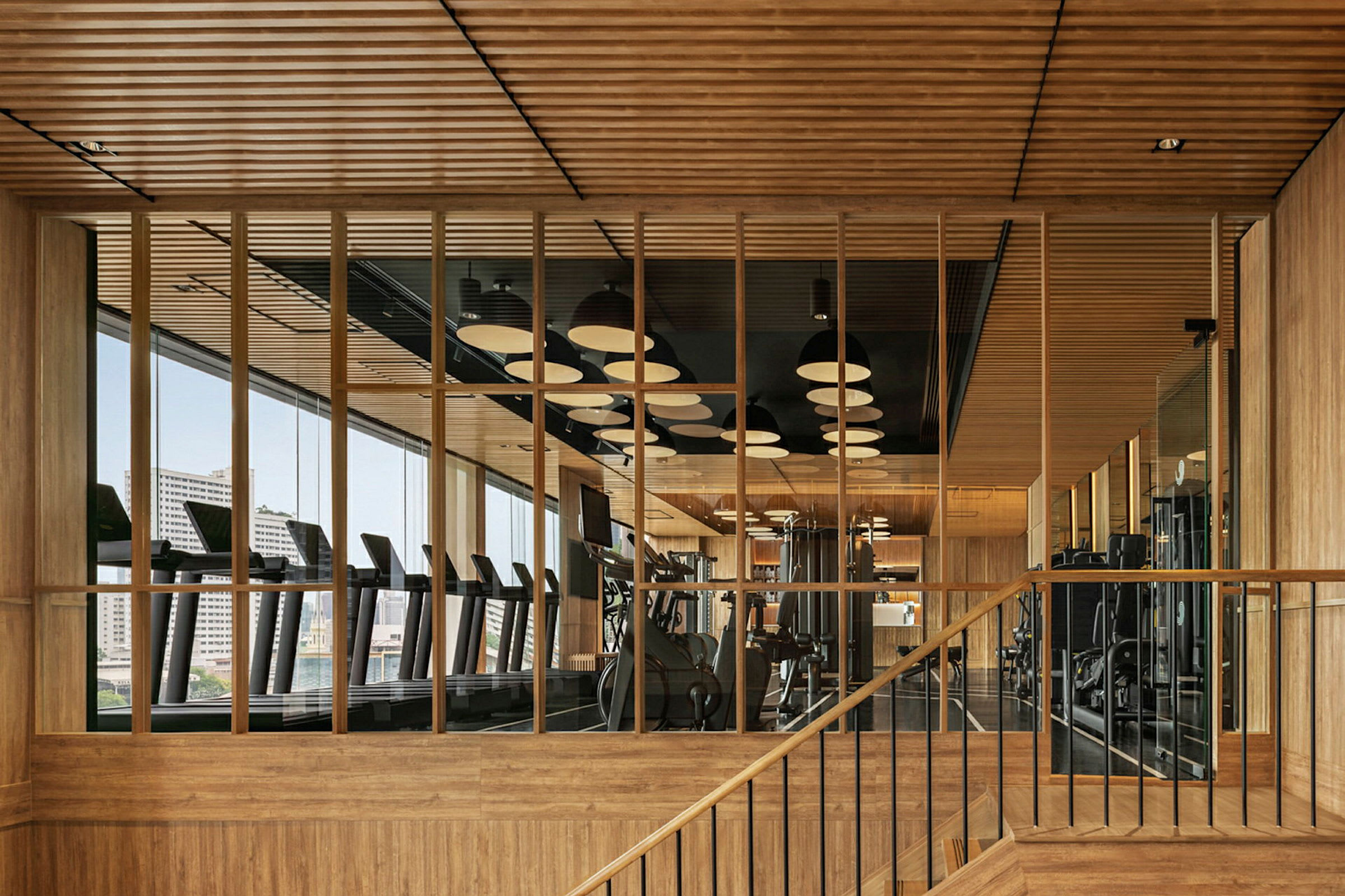Ett modernt gym med trädetaljer och stora fönster. (AI-genererad text)