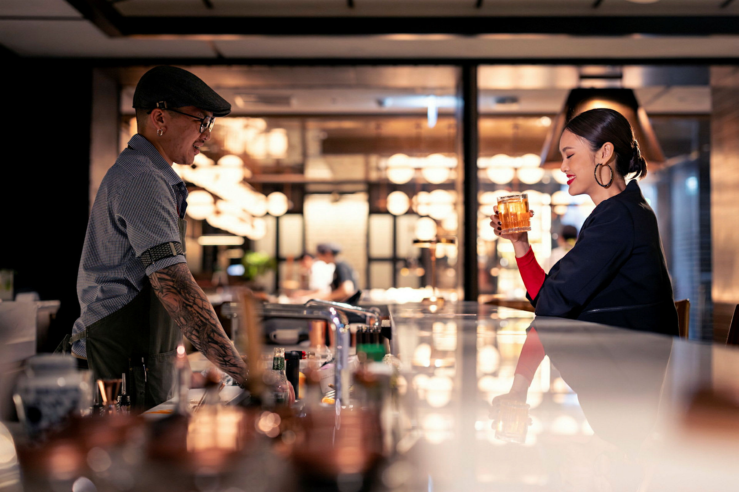 En bar med en bartender i mössa och en gäst som håller ett glas dryck. (AI-genererad text)