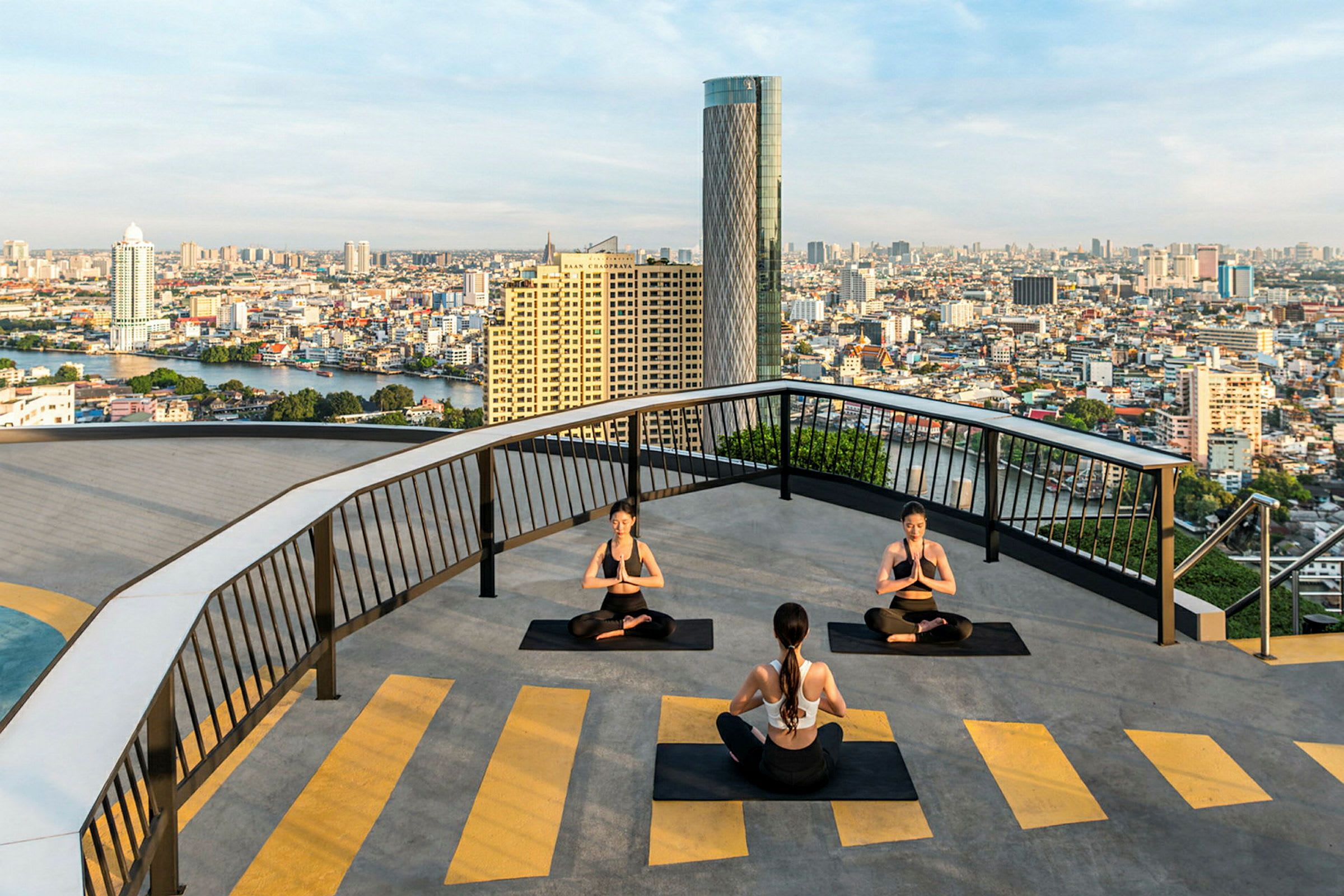 Personer som utför yoga på en takterrass med utsikt över en stad. (AI-genererad text)