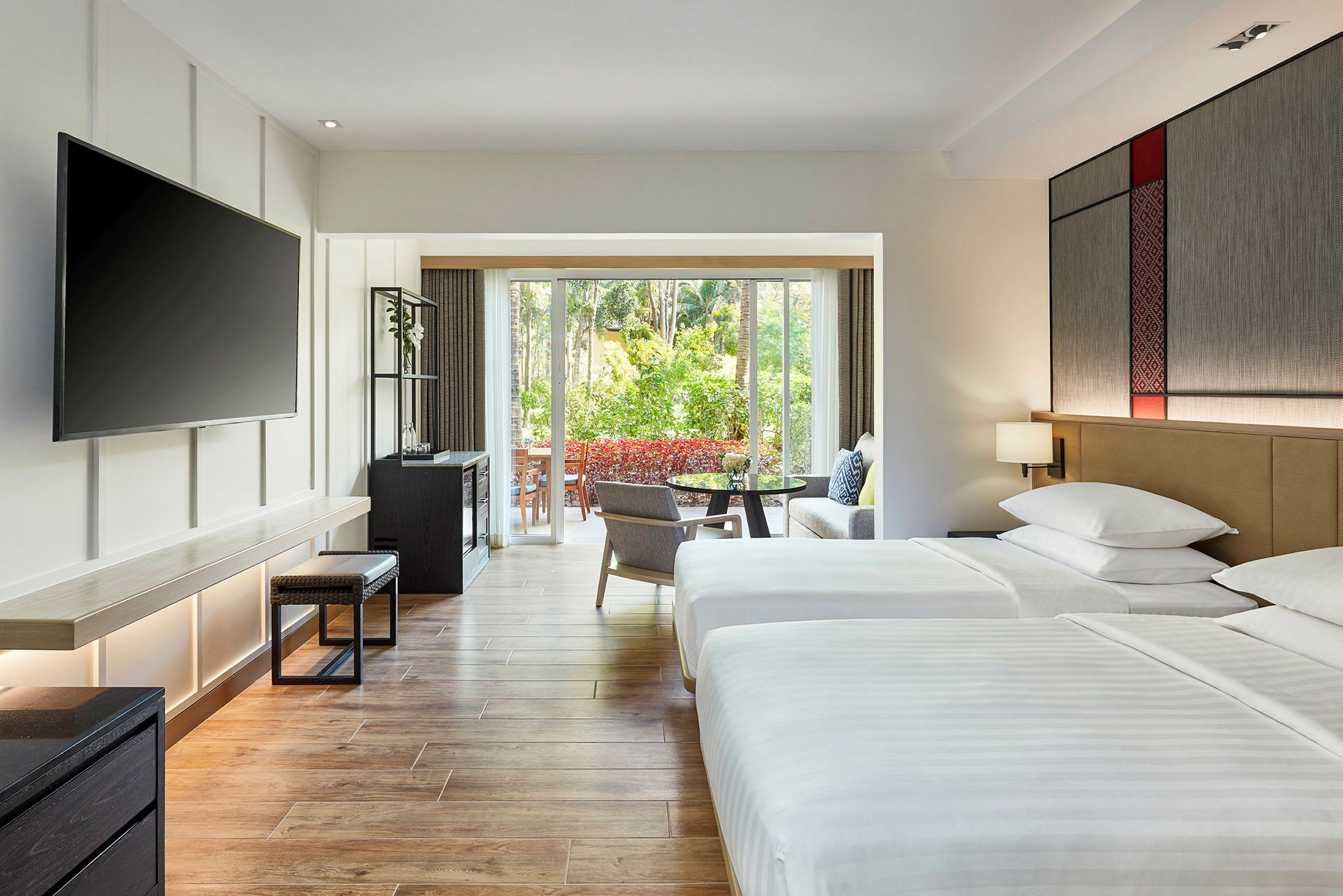 Hotellrum med två sängar, ett stort fönster som vetter mot en grönskande trädgård. (AI-genererad text)