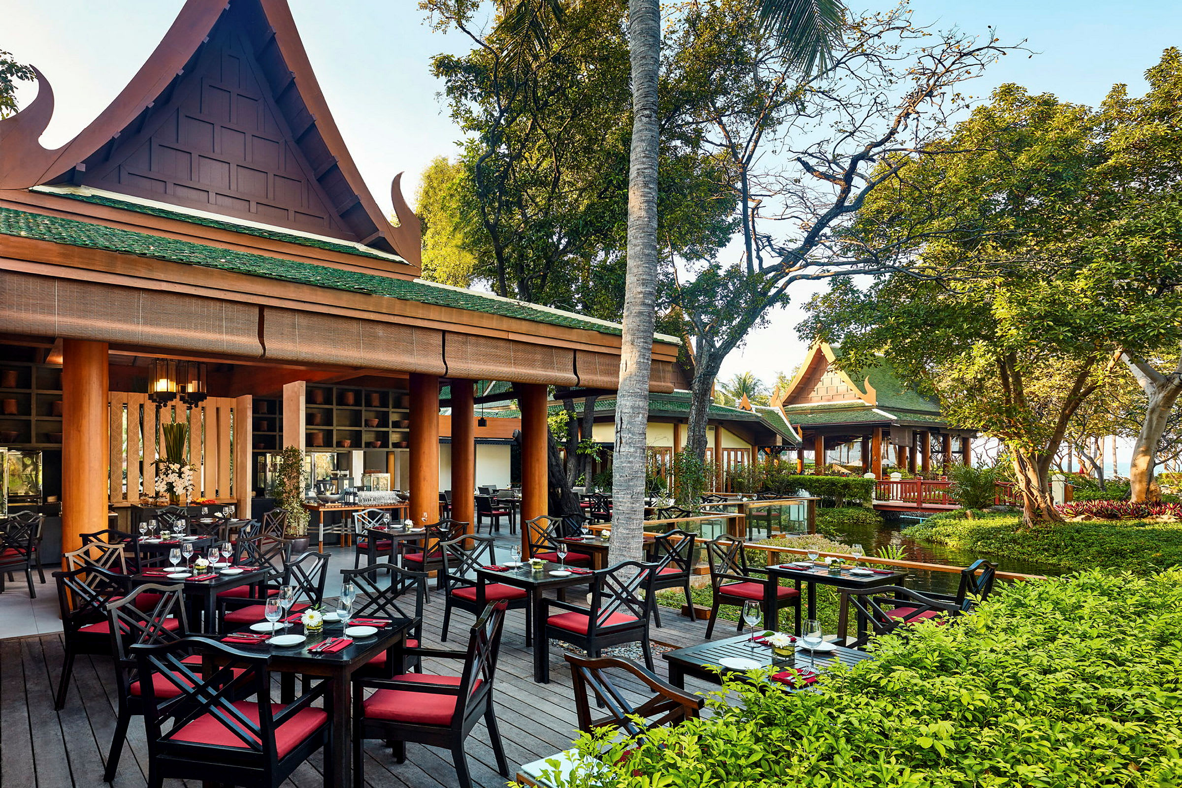 Utomhusrestaurang med traditionellt asiatisk arkitektur omgiven av grönska. (AI-genererad text)