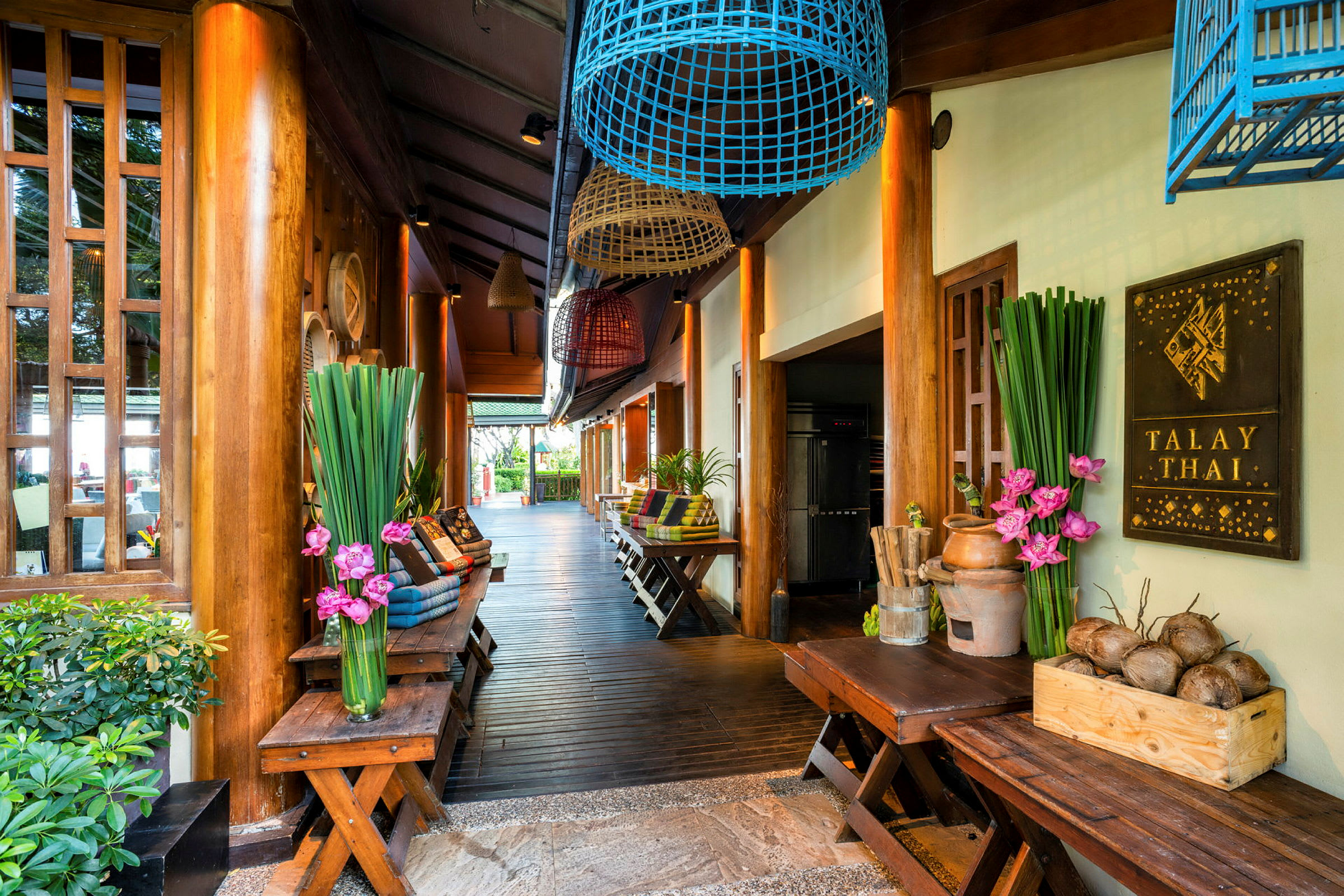 Ingång till en thailändsk restaurang med trädetaljer, växter och dekorationer. (AI-genererad text)