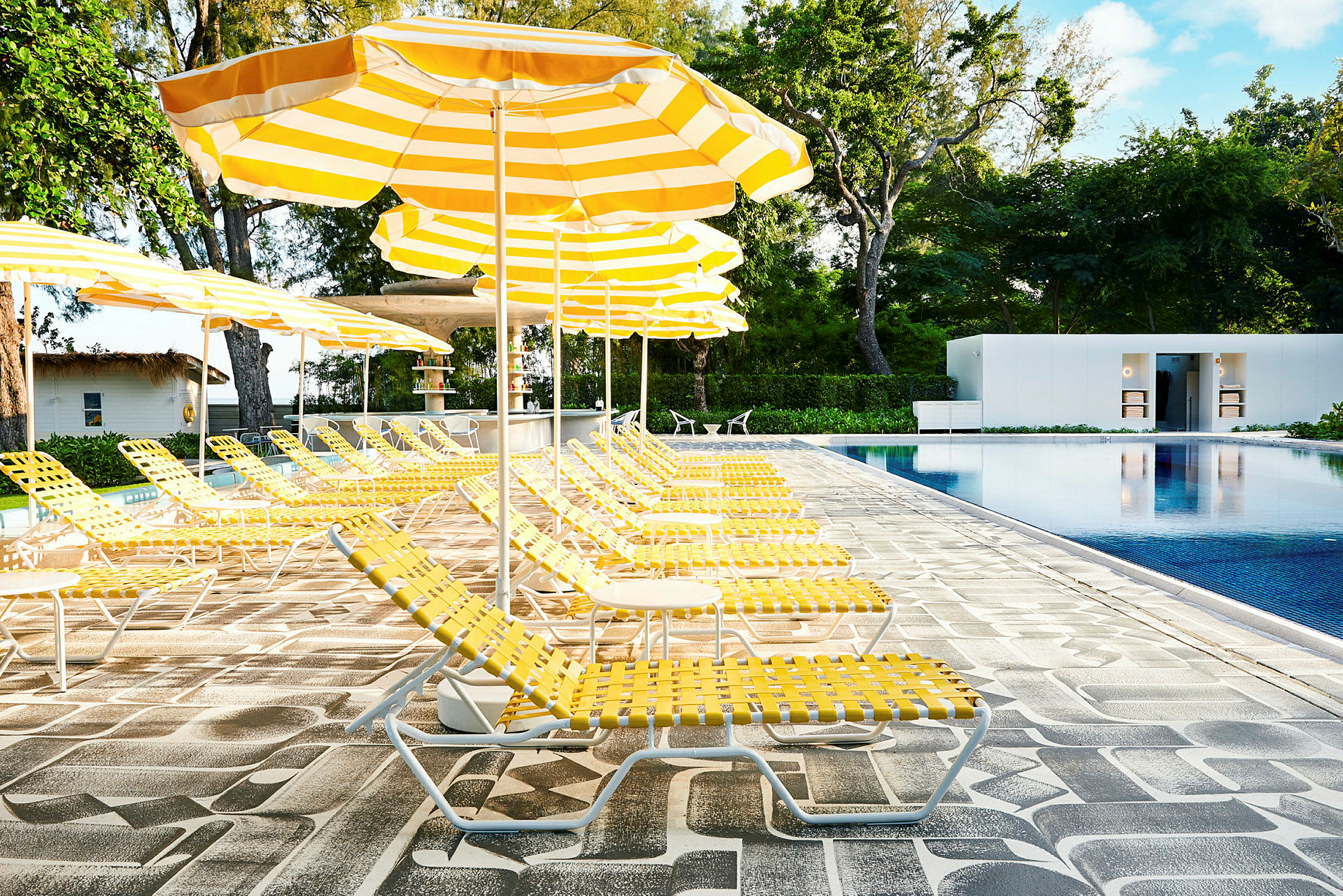 Solstolar och parasoller vid en swimmingpool utomhus. (AI-genererad text)