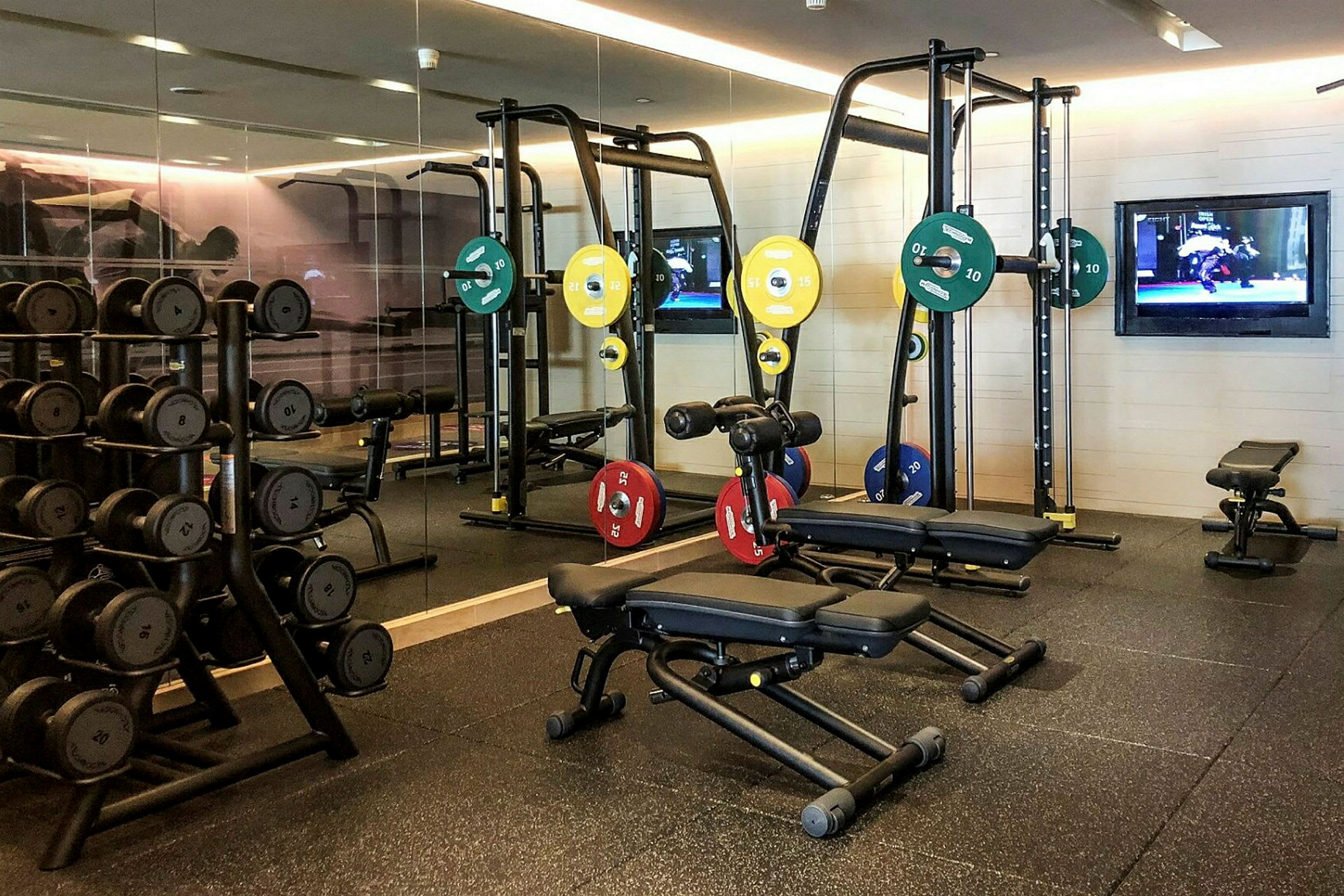 Bild på ett gym med träningsutrustning som vikter, bänkar och maskiner. (AI-genererad text)