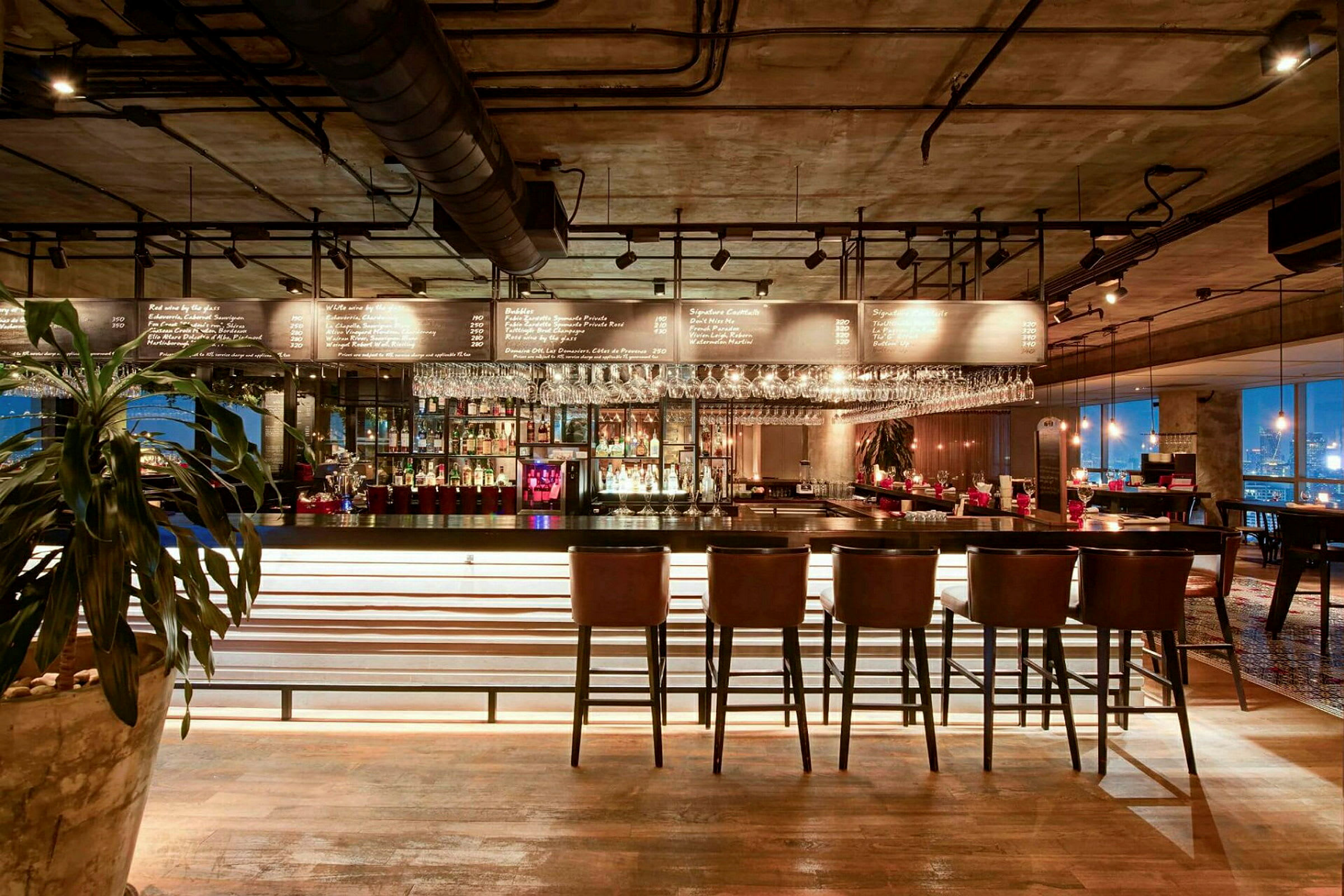 Interiör av en modern bar med stolar vid en bänk och hyllor med flaskor och glas. (AI-genererad text)