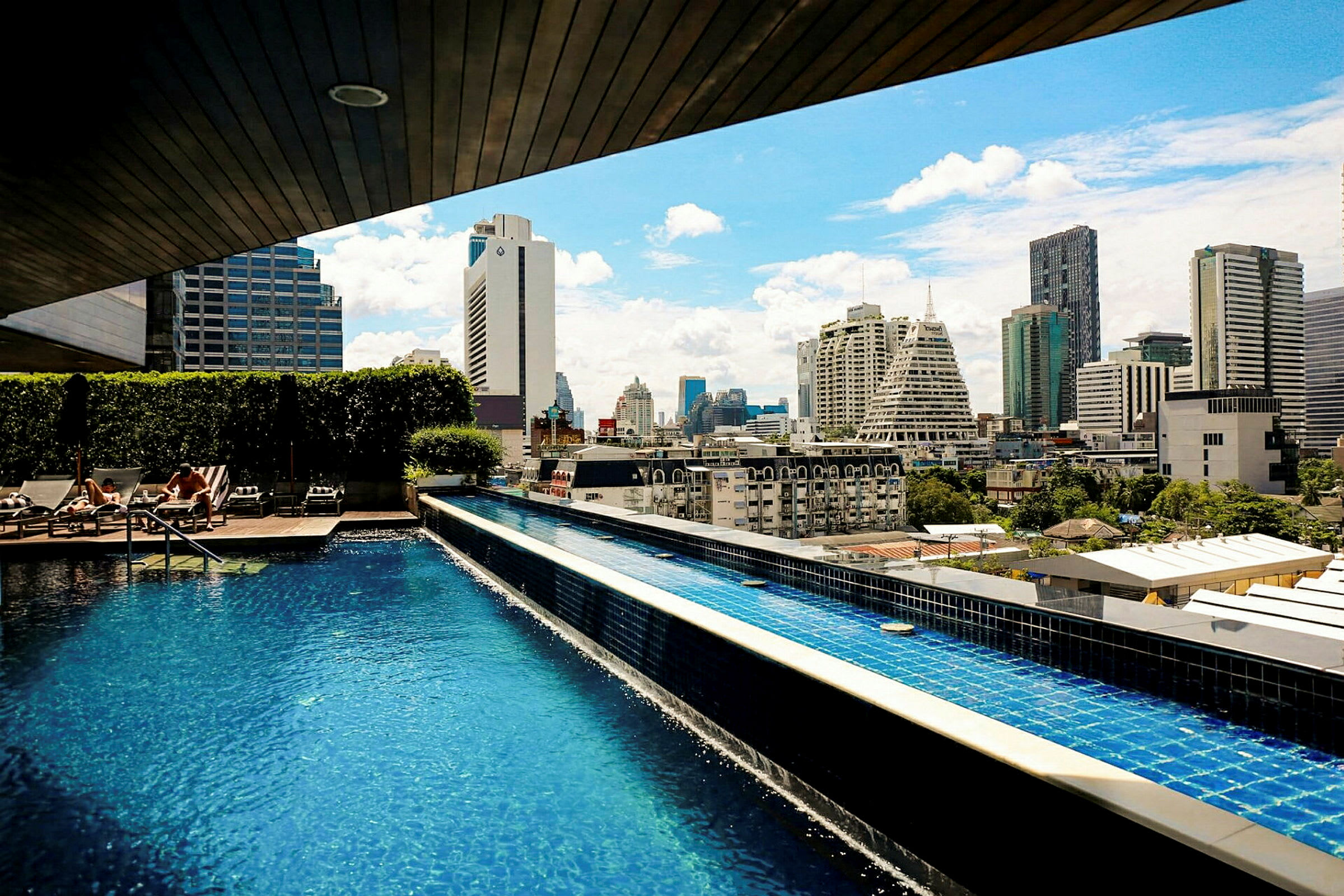 En pool på ett tak med utsikt över stadens skyline under en solig himmel. (AI-genererad text)