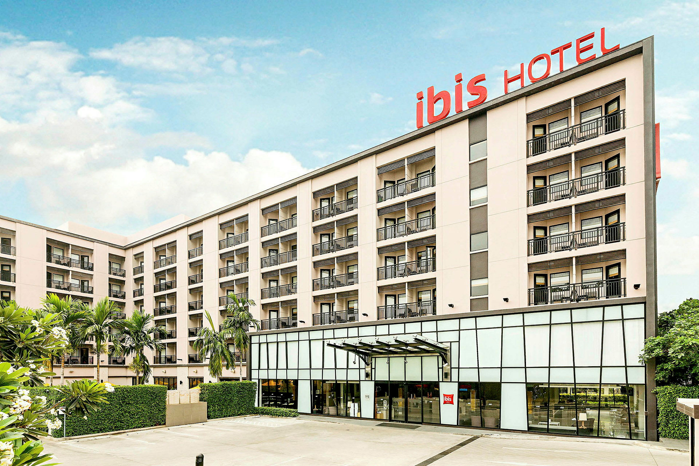 Hotellbyggnad med flera våningar och balkonger, skylt med texten 'ibis HOTEL'. (AI-genererad text)