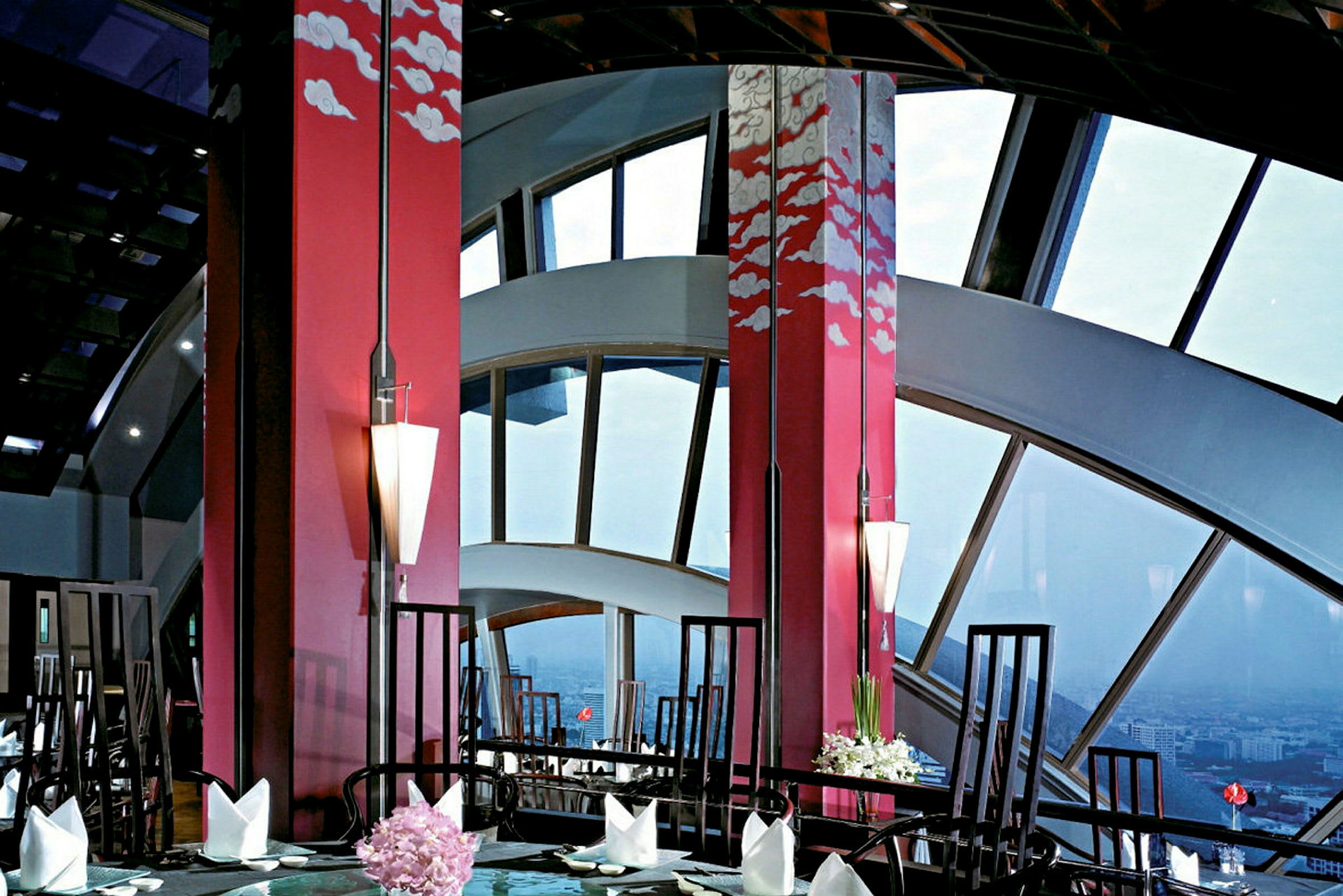 En elegant restaurang med stora fönster och röd inredning dekorerad med konstnärliga molnmotiv. (AI-genererad text)