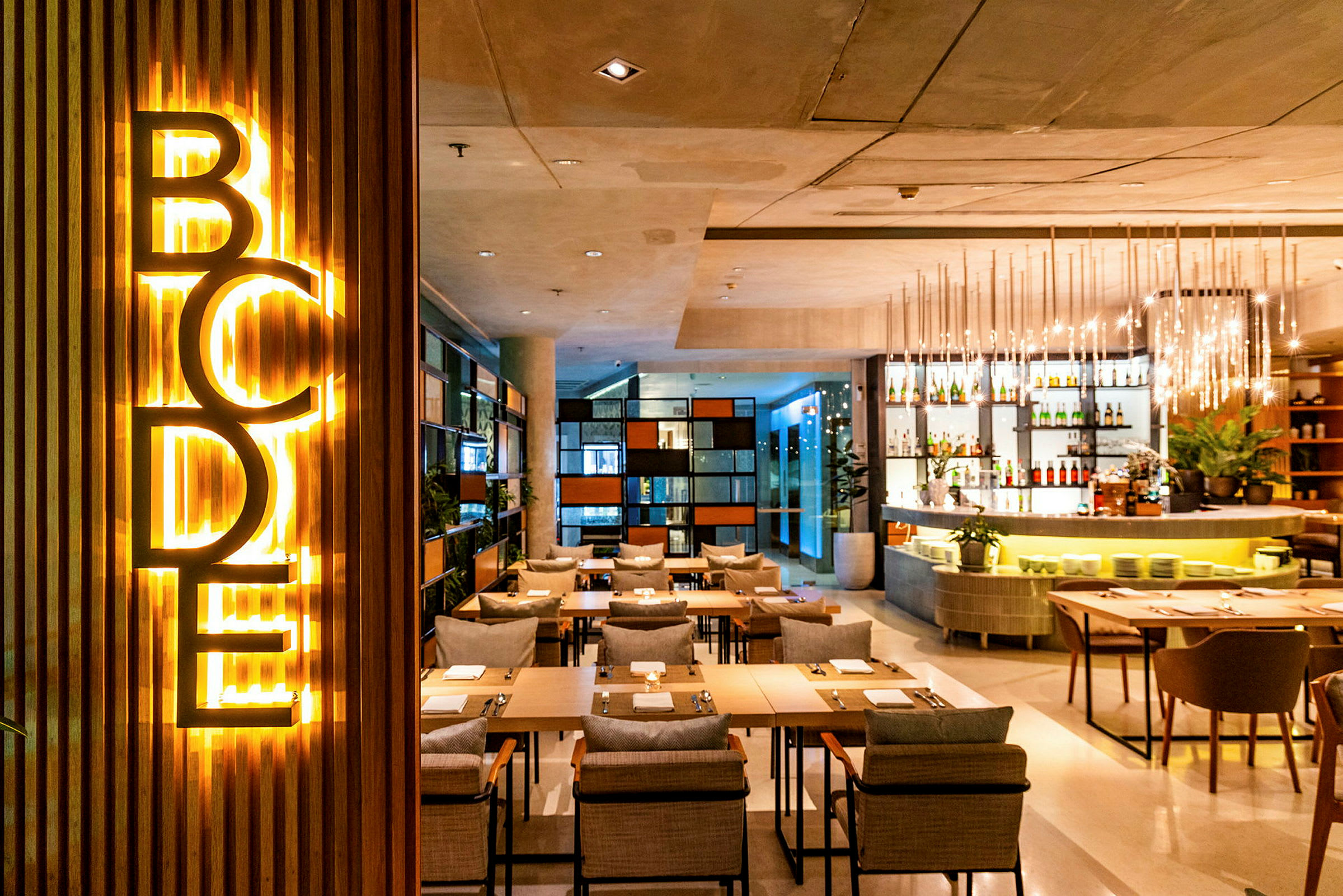Ett modernt restaurangområde med belysning, sittplatser och en bardisk. (AI-genererad text)