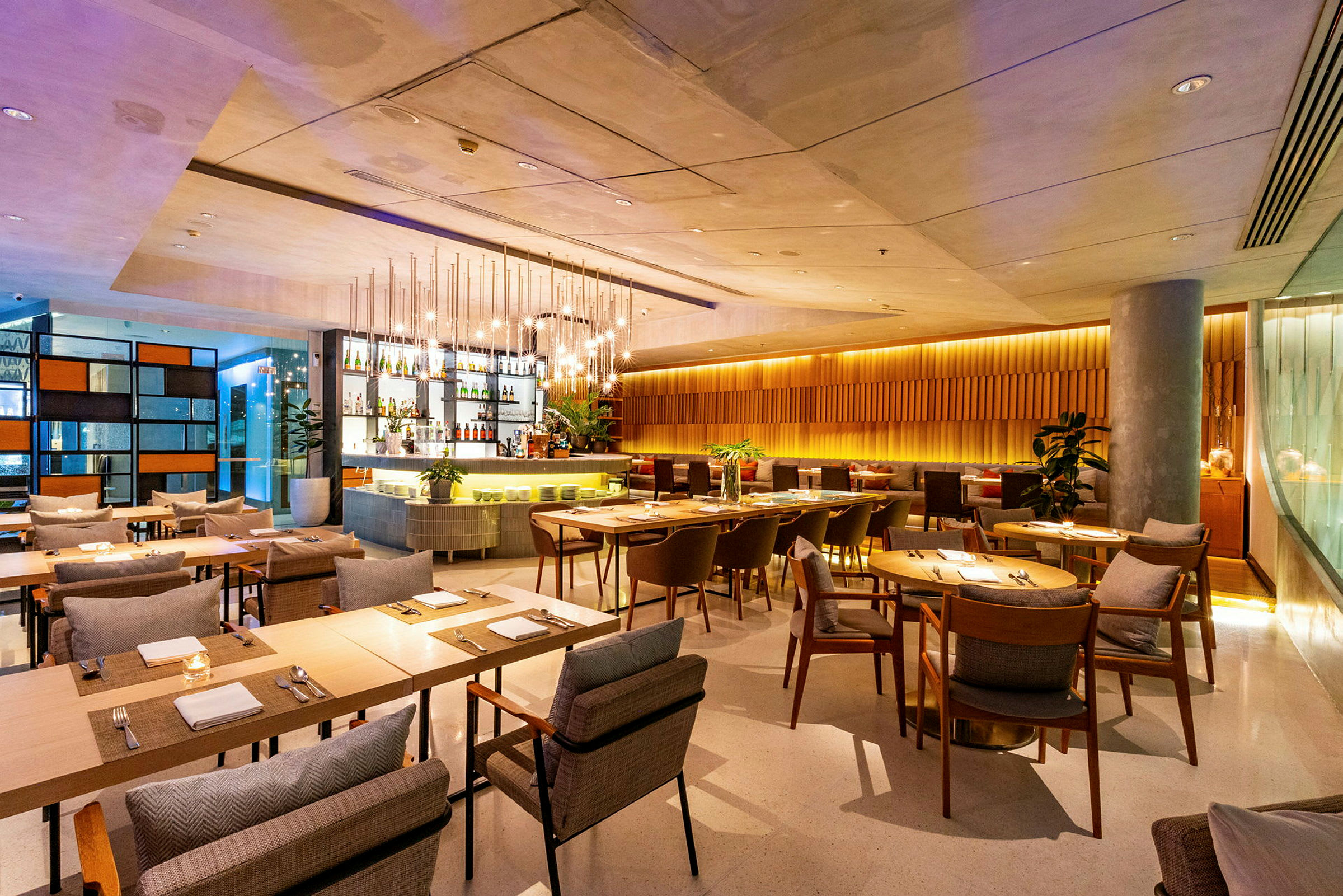 En modern restaurang med träbord, bekväma stolar och en stilfull bar i bakgrunden. (AI-genererad text)