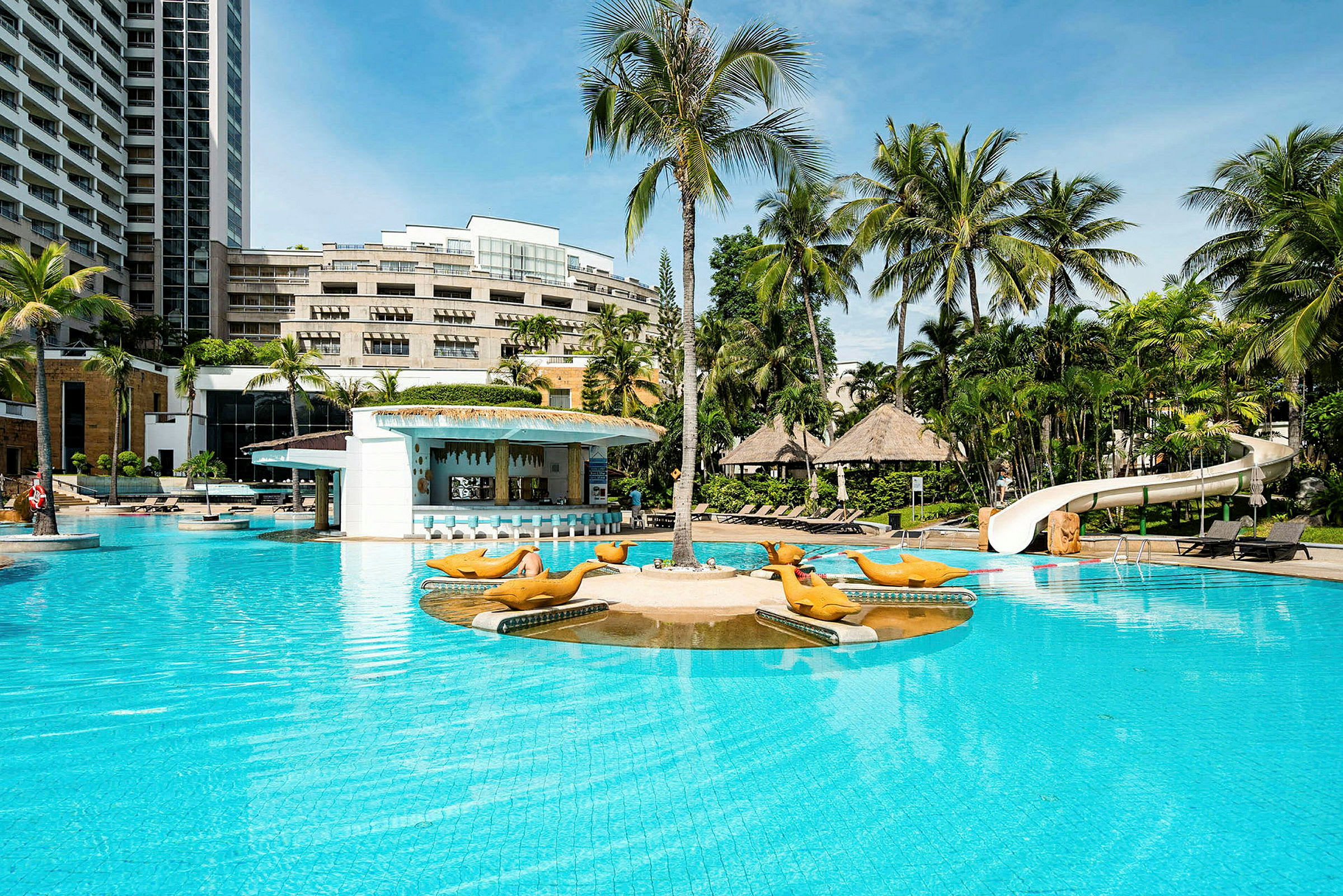 Bild av en hotellpool med palmer och solstolar i bakgrunden. En lekplats och vattenrutschbana syns vid ena kanten av poolen. (AI-genererad text)