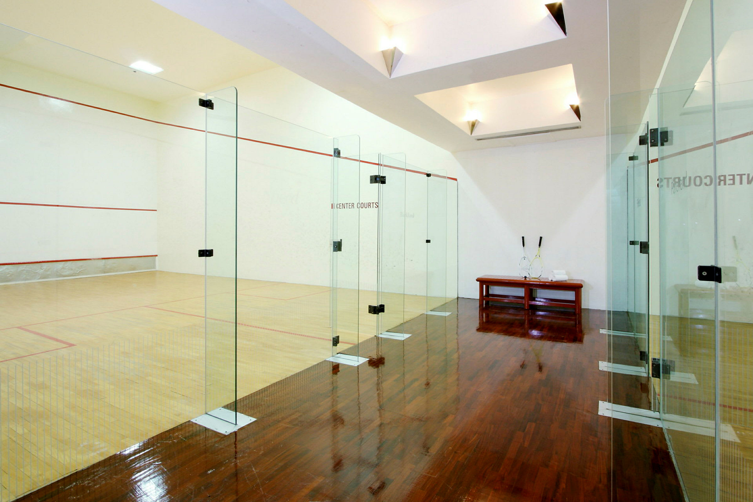 Squashhall med glasväggar och trägolv. (AI-genererad text)