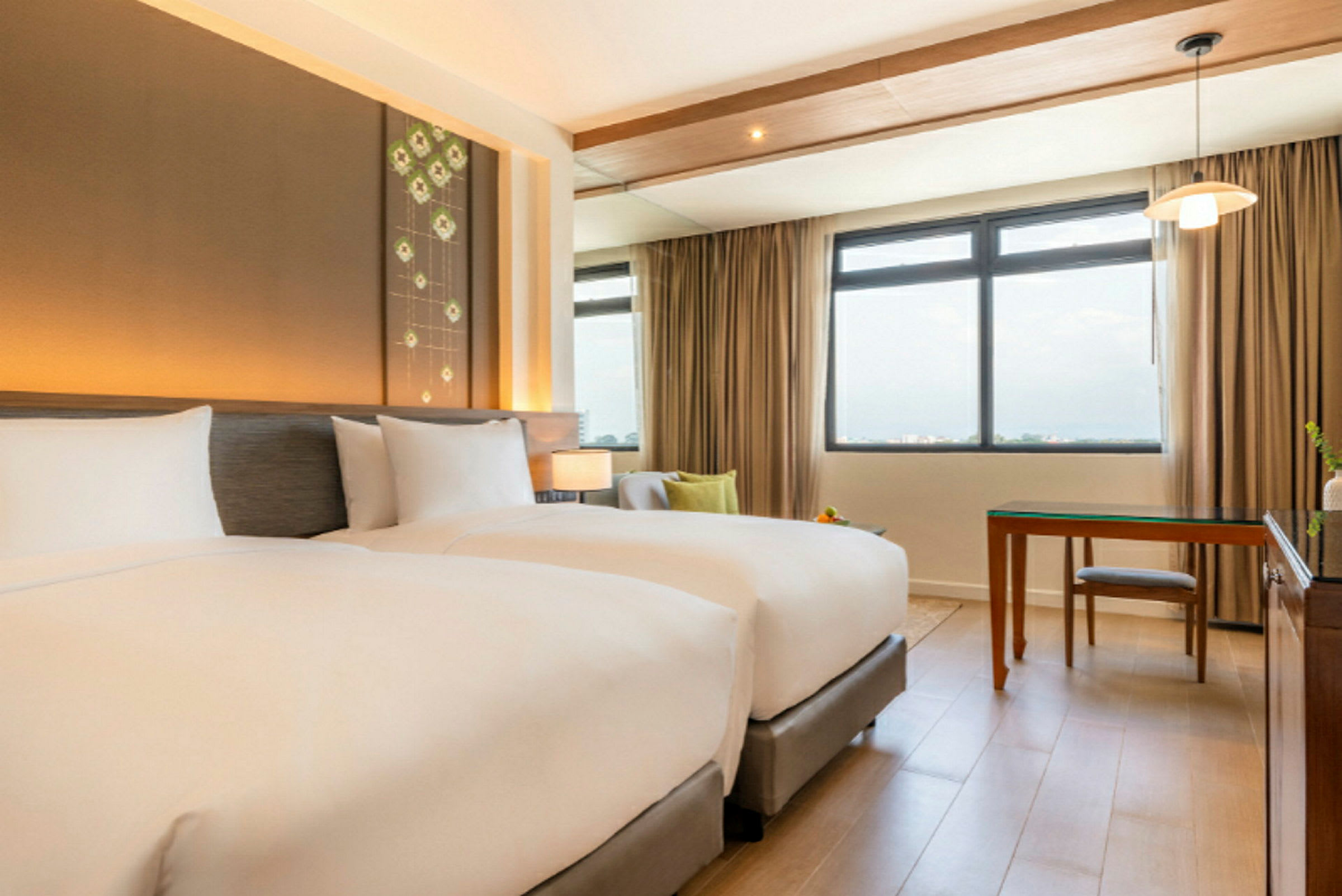 Ett hotellrum med två enkelsängar, ett stort fönster och ett skrivbord. (AI-genererad text)