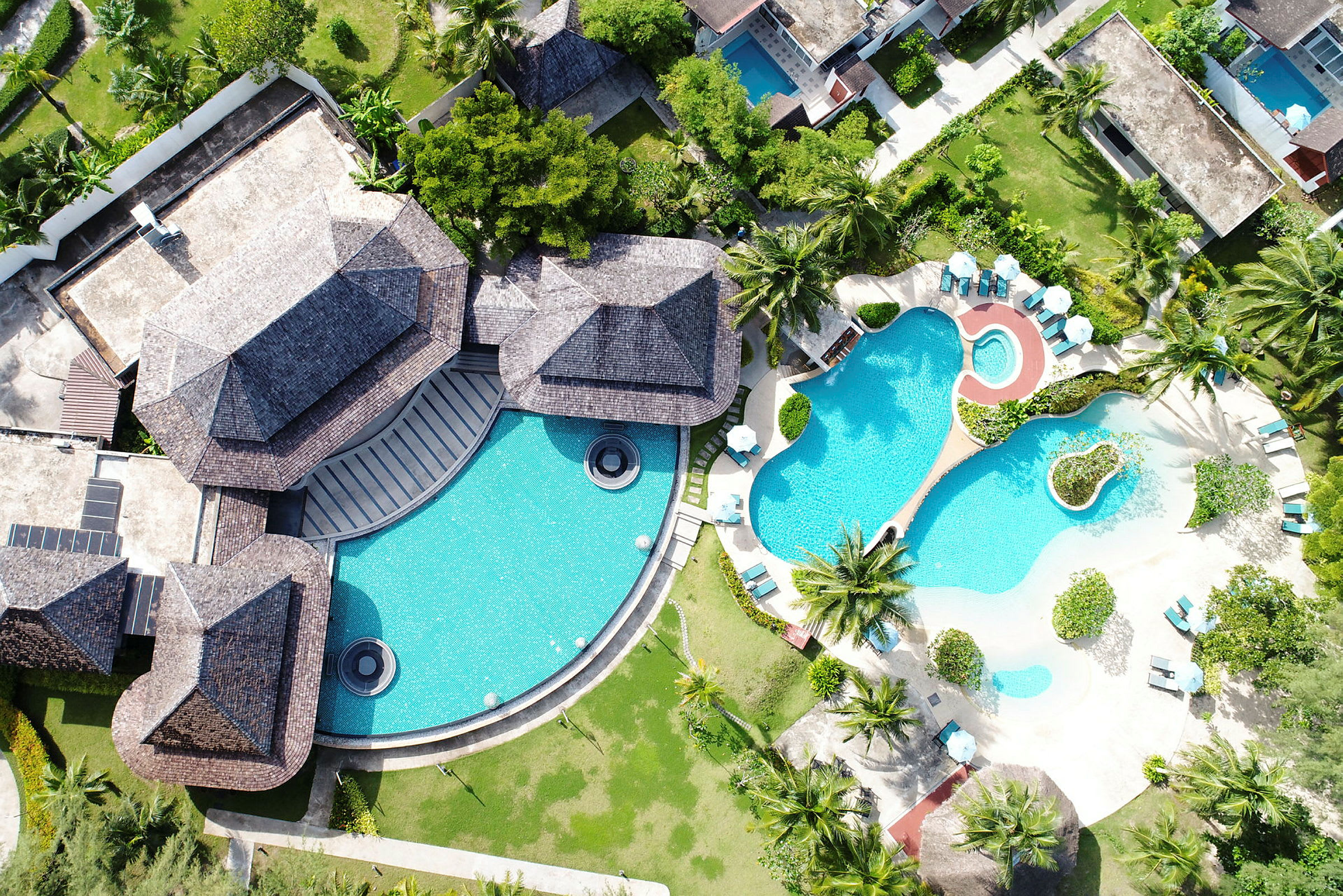 Fågelperspektiv av en resort med pooler och grönska. (AI-genererad text)