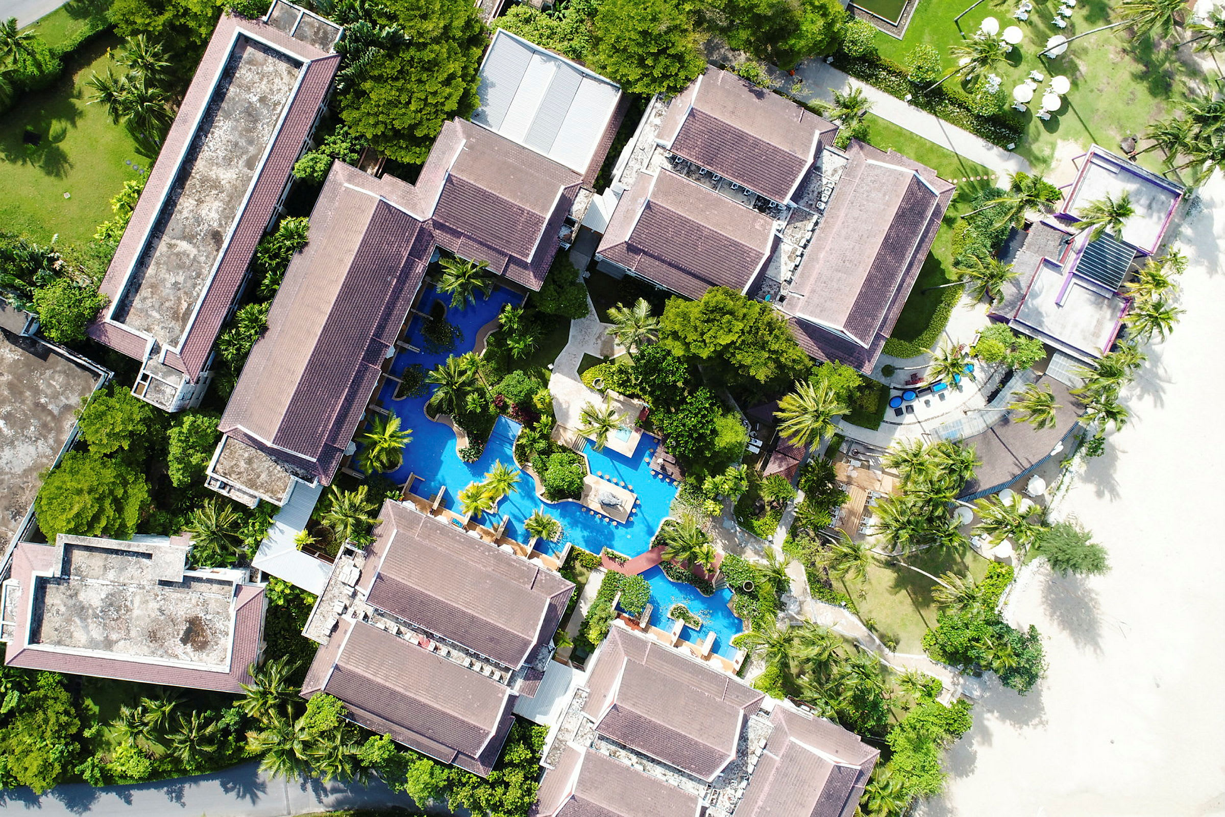 Flygfoto över en resort med pool och närliggande strand. (AI-genererad text)