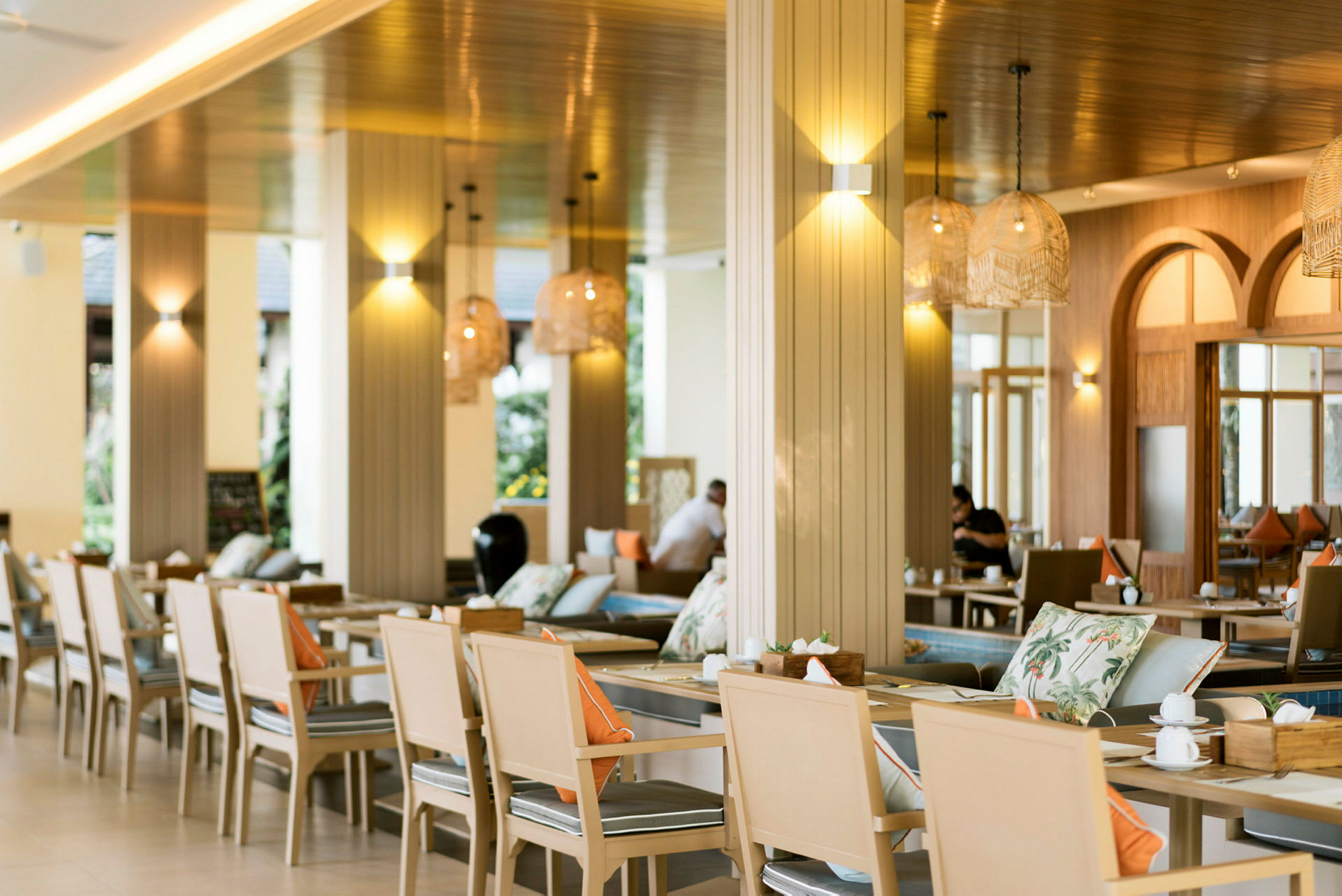 En restaurang med bord och stolar, dekorerad med lampor och kuddar. (AI-genererad text)