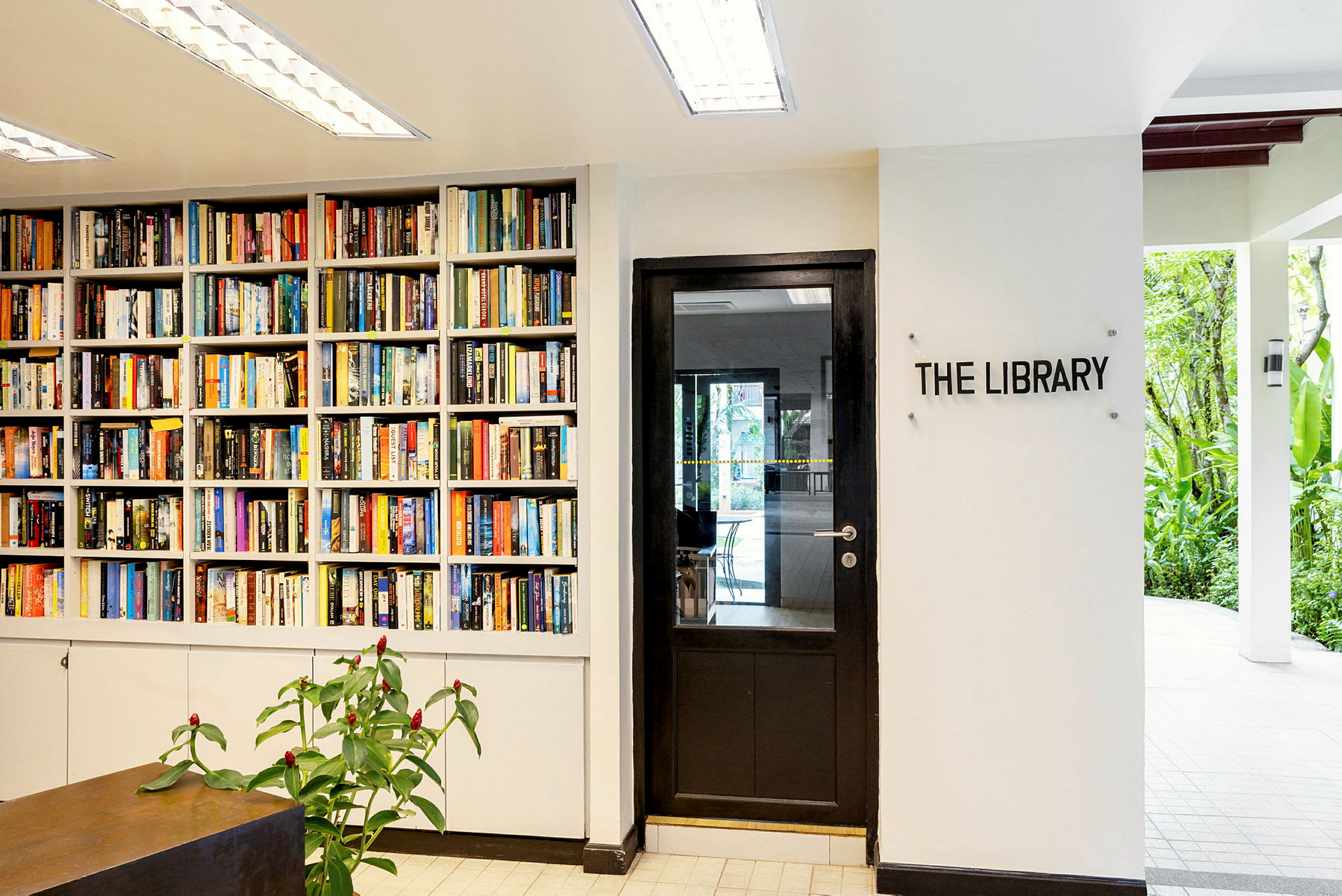 En bokhylla fylld med böcker vid sidan av en dörr med skylten "The Library". (AI-genererad text)