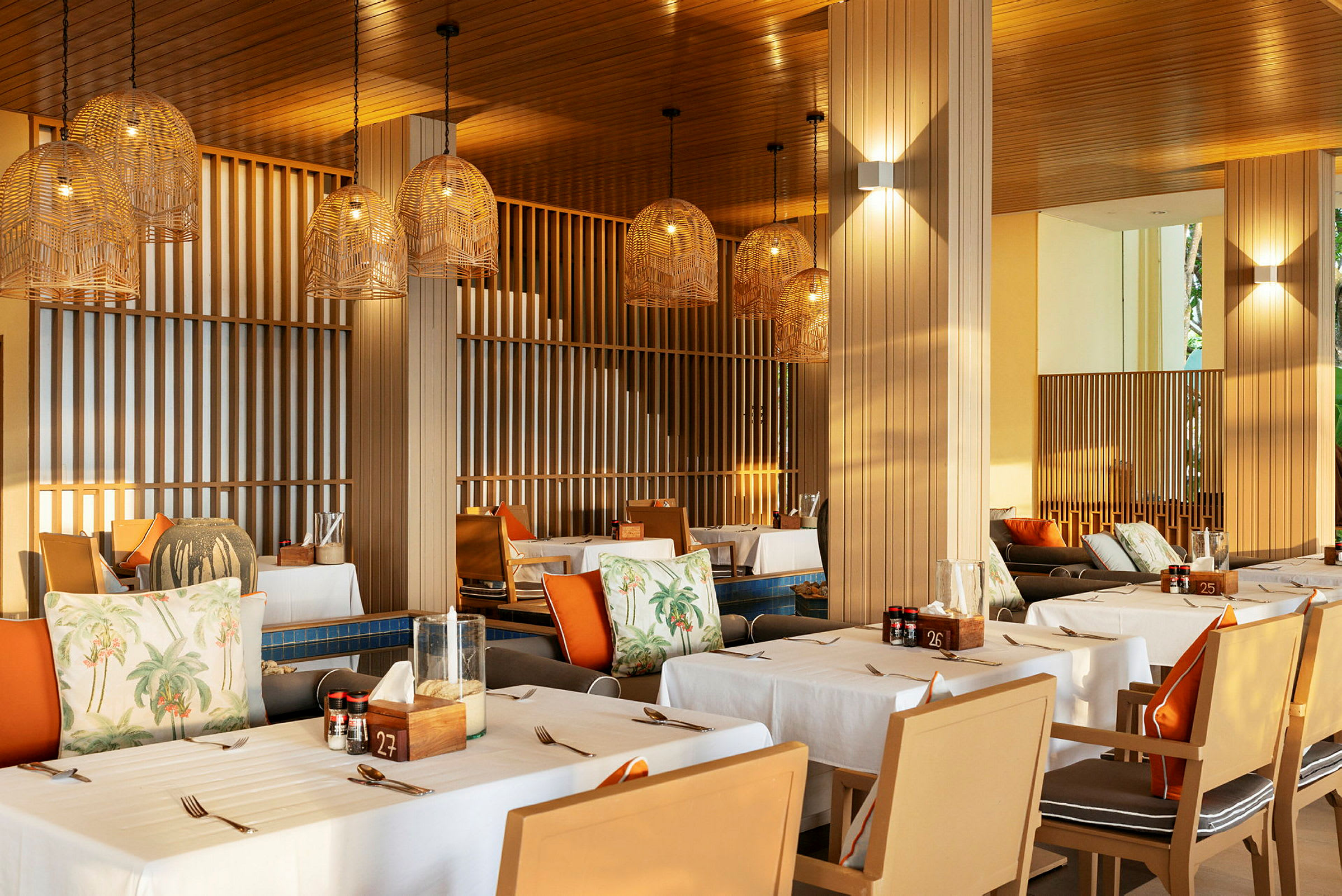 En restaurang med dukade bord och hängande lampskärmar i flätad design. (AI-genererad text)