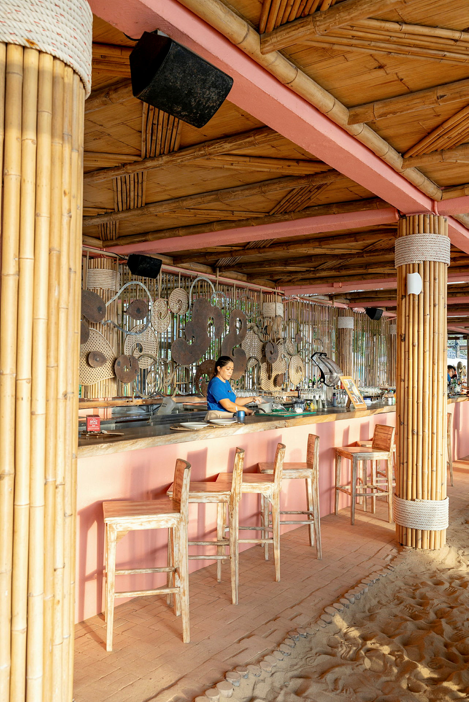 En strandbar med stolstolar och dekorativ inredning av bambu och flätade mönster. (AI-genererad text)