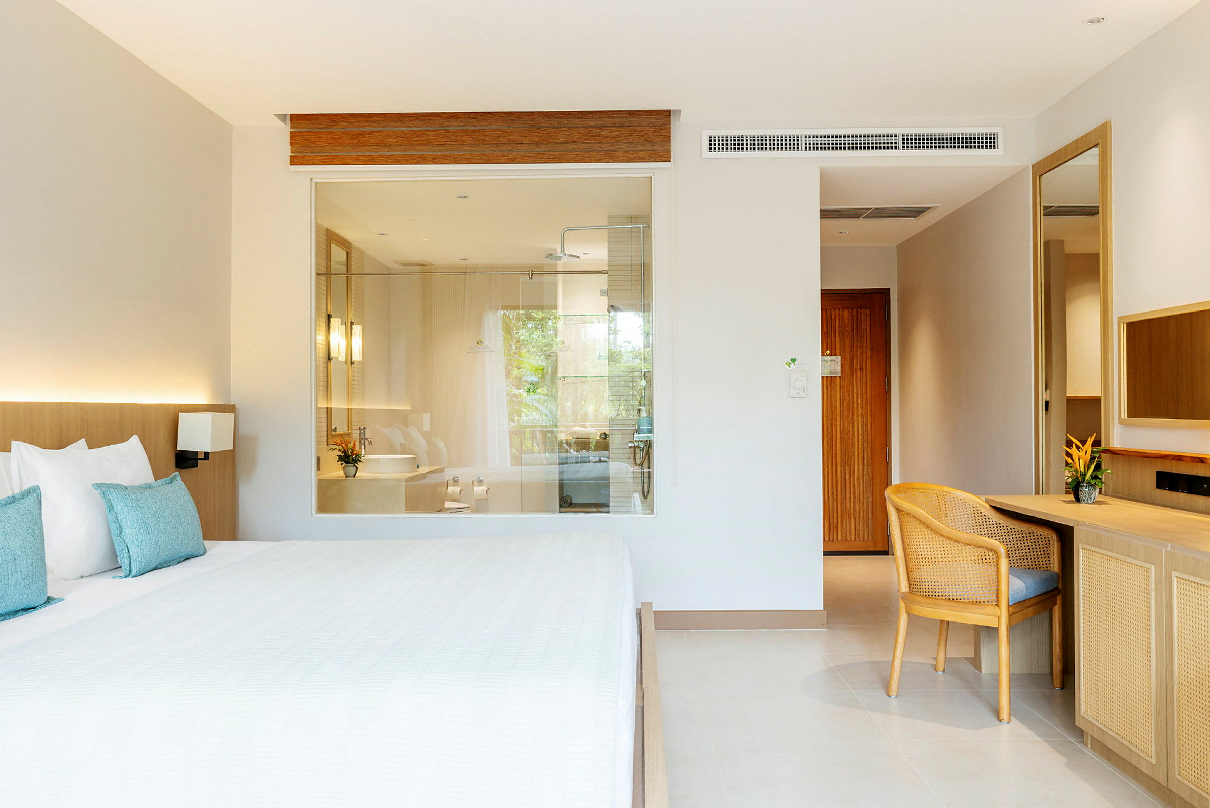 Hotellrum med säng, skrivbord och en glasvägg till badrummet. (AI-genererad text)