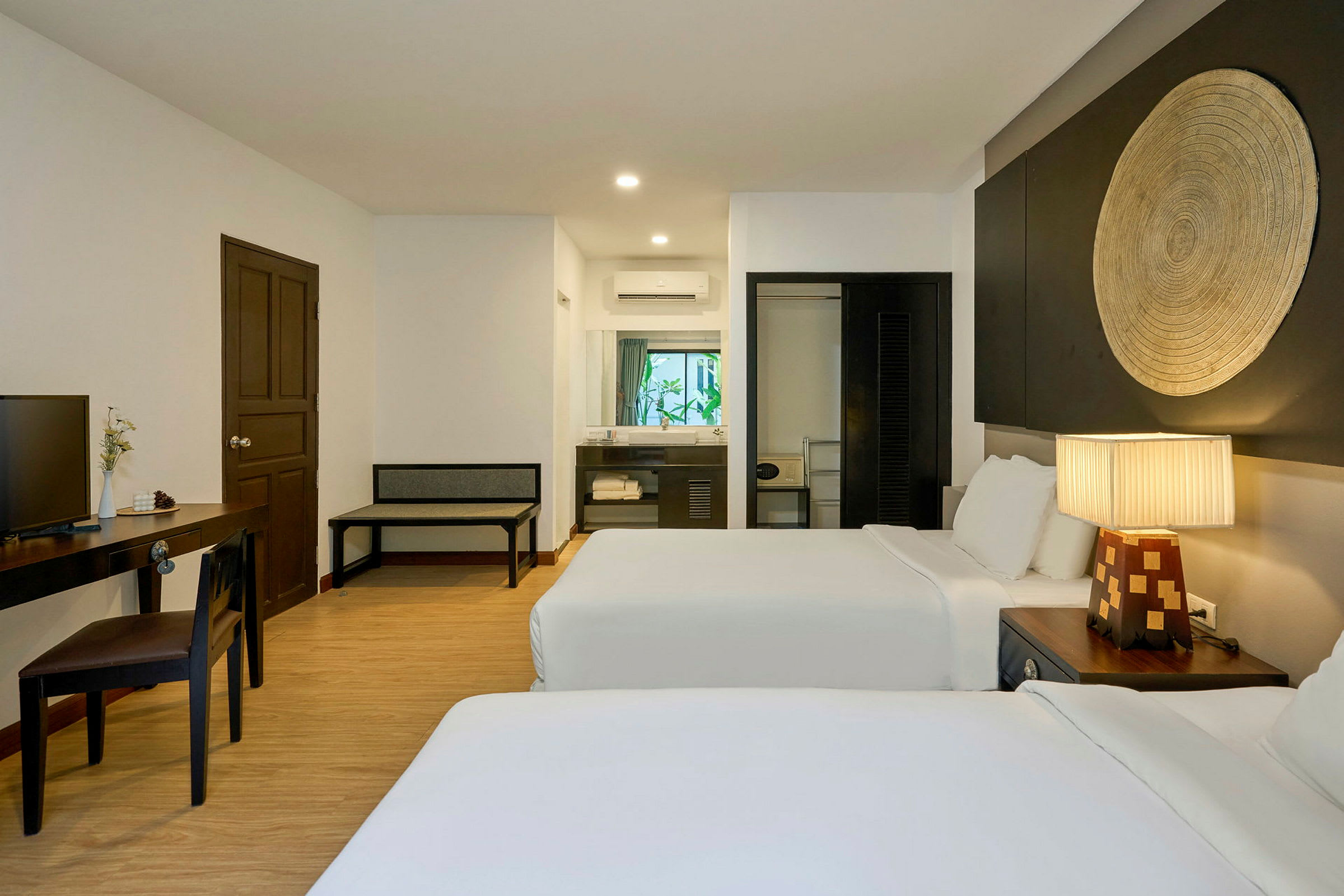 Hotellrum med två sängar, skrivbord, stol, fönster och dekorativt väggelement. (AI-genererad text)