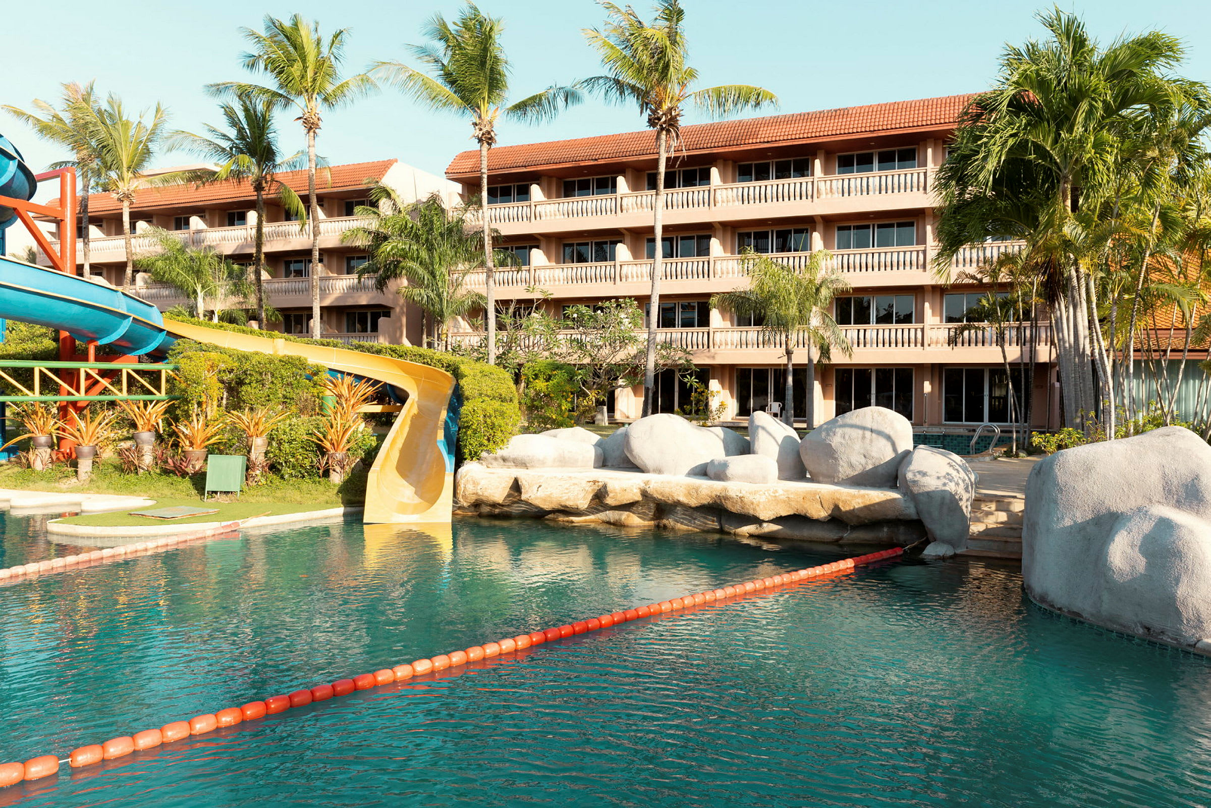 Pool med vattenrutschkana nära hotell med flera våningar. (AI-genererad text)