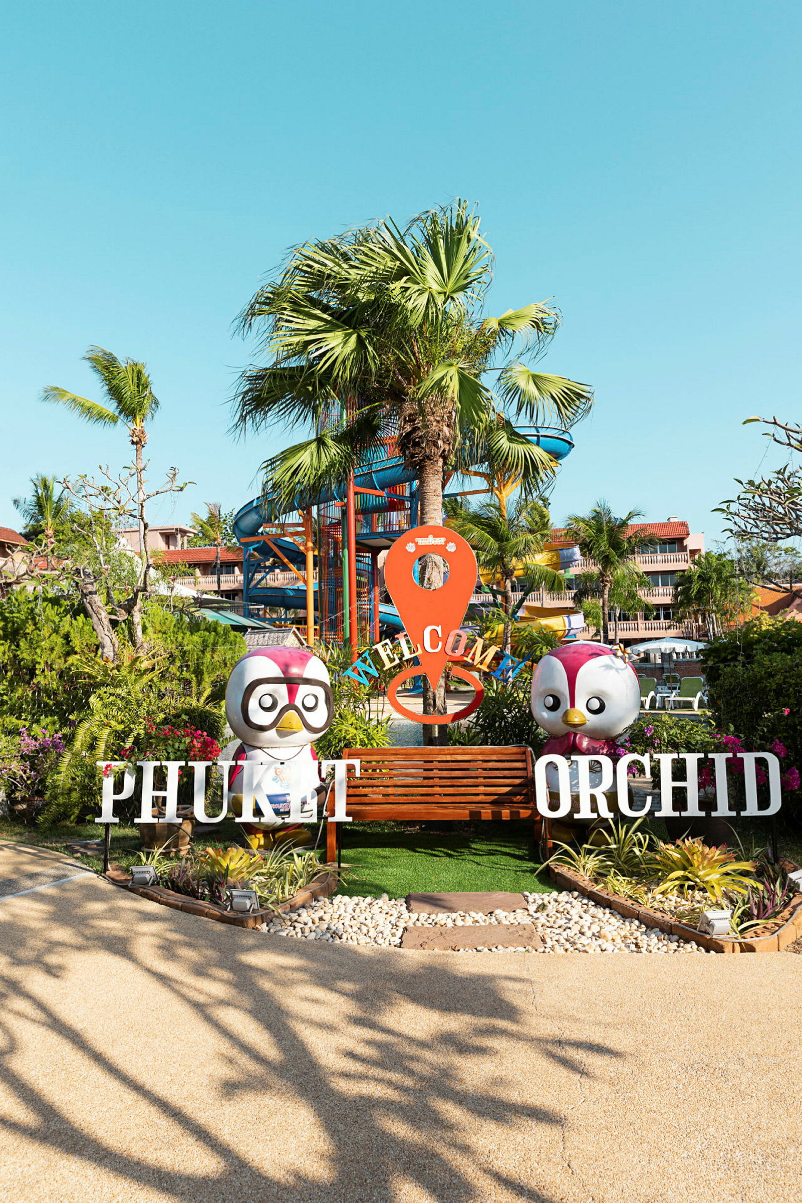 Ingång till Phuket Orchid med palmer i bakgrunden. (AI-genererad text)