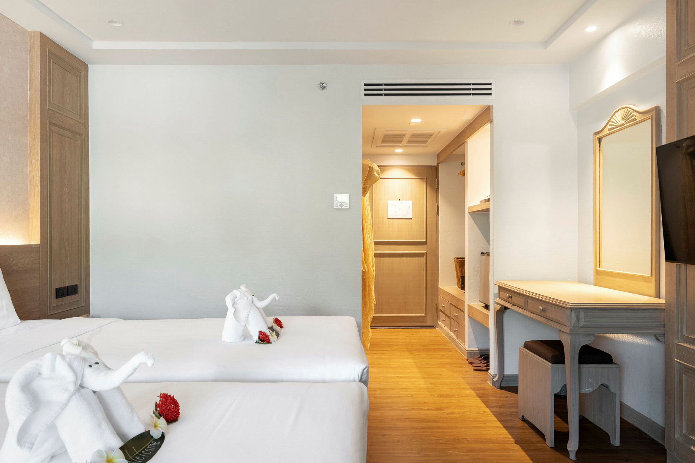 Hotellrum med två enkelsängar, dekorerade med handdukssfigurer. Inredning inkluderar skrivbord och ingång till garderob. (AI-genererad text)