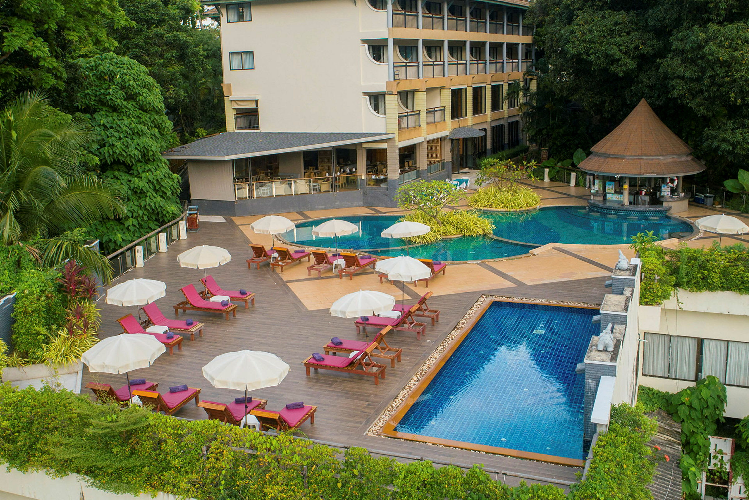 Vy över hotellpoolområde med solstolar, parasoller och två pooler. (AI-genererad text)