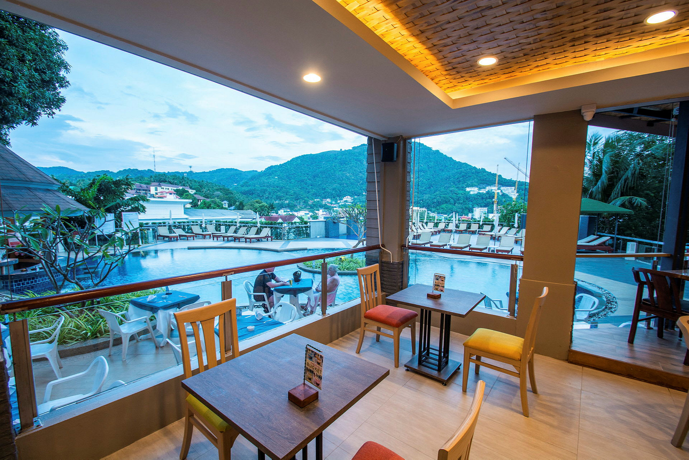 En restaurang med utsikt över en pool och berg i bakgrunden. (AI-genererad text)