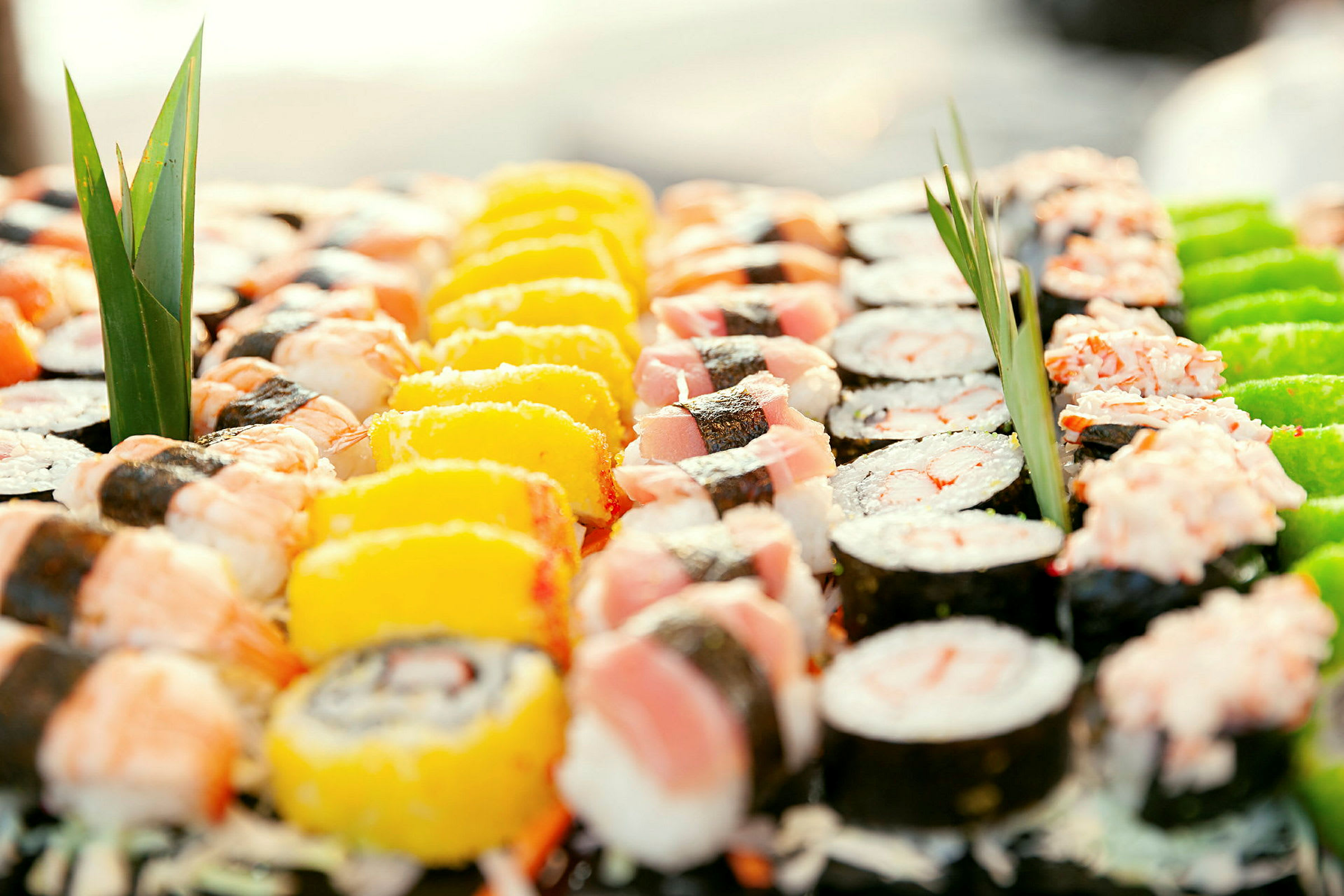 En närbild av olika sorters sushi upplagt med dekorativa blad. (AI-genererad text)