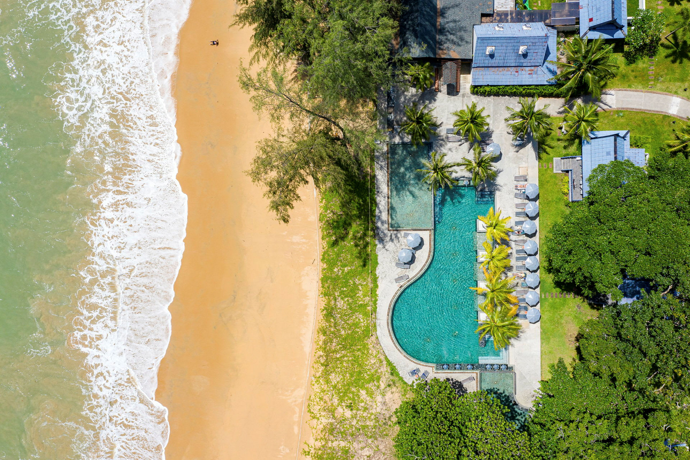 Flygbild av en resort med en pool bredvid en sandstrand. (AI-genererad text)