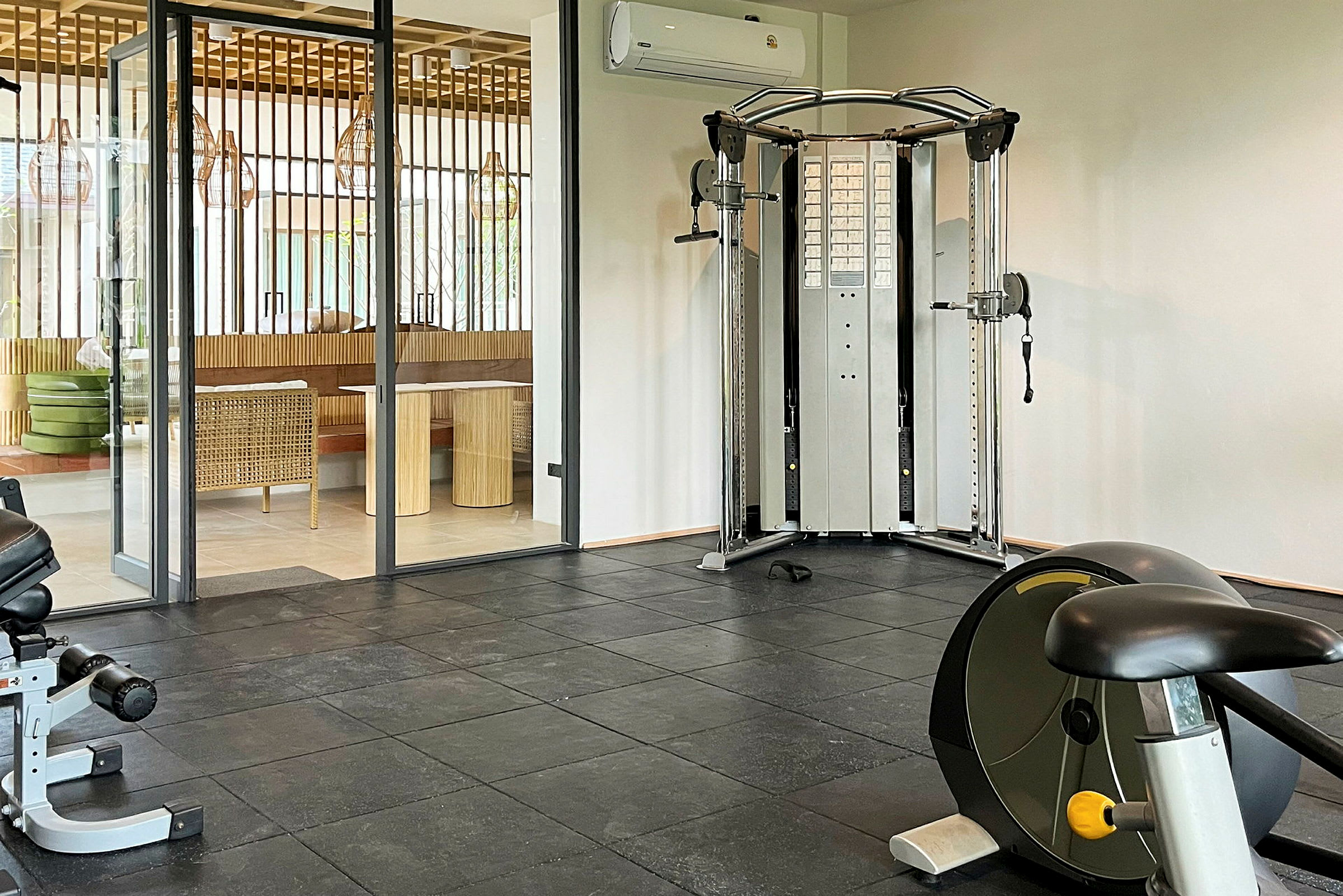 Ett gym med träningsmaskiner och en glasdörr som leder till ett möblerat rum. (AI-genererad text)