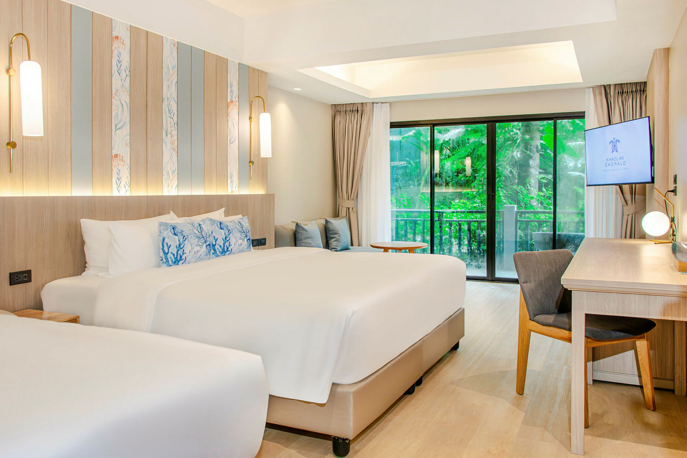 Ett modernt hotellrum med två sängar, skrivbord och skjutdörrar mot en grönskande utsikt. (AI-genererad text)