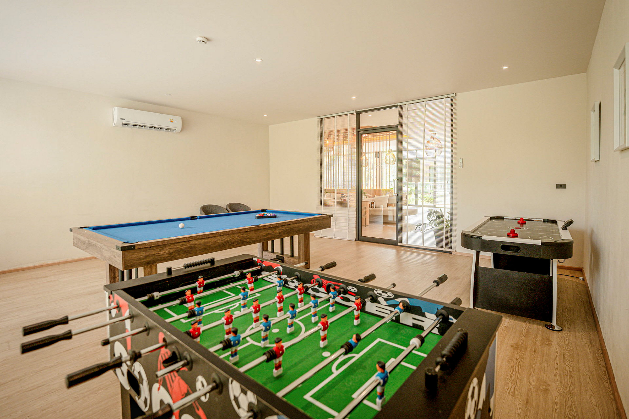 Ett spelrum med ett biljardbord, ett fotbollsspel och ett air hockey-bord. (AI-genererad text)