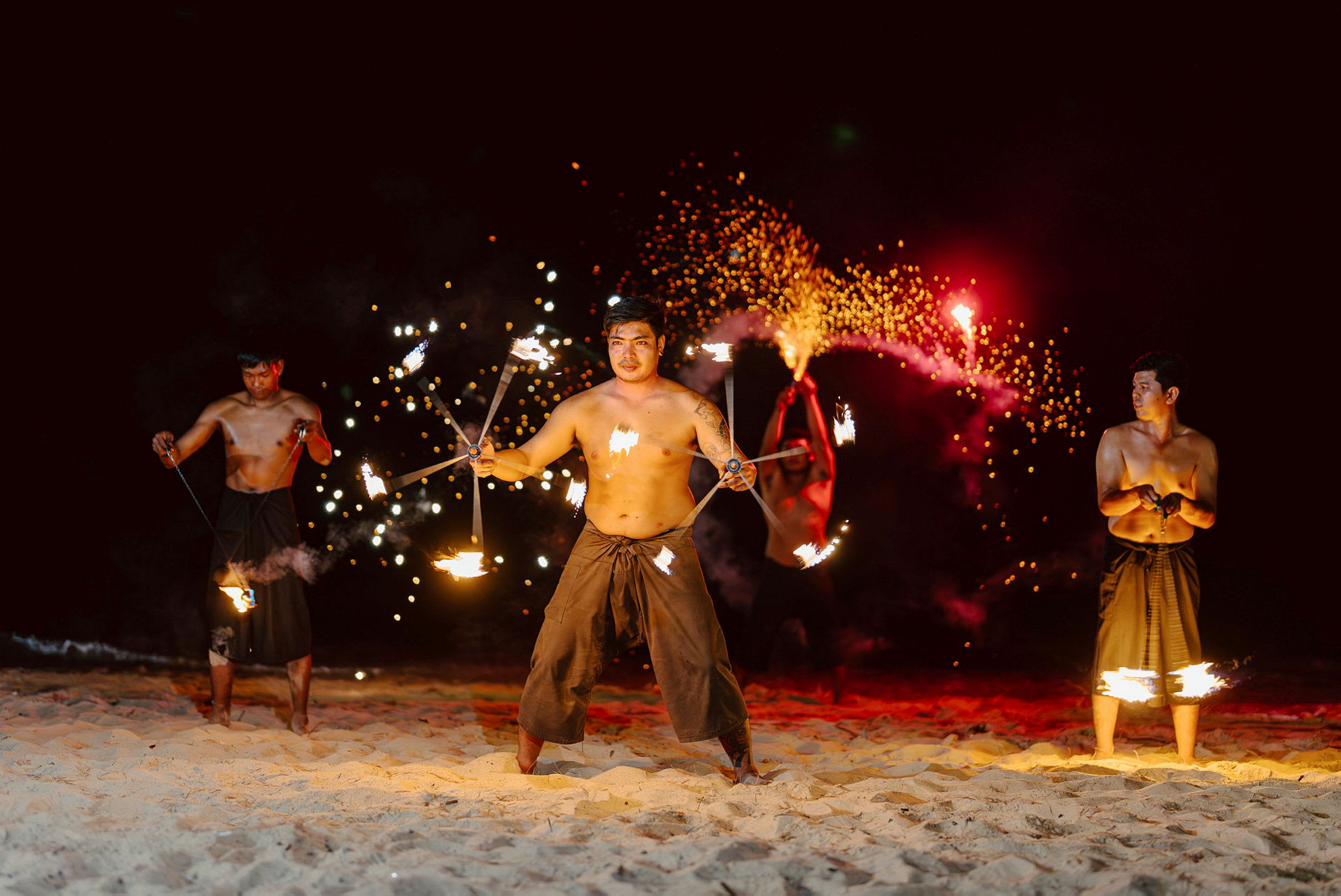 Män utför en eldshow på en sandstrand under natten. (AI-genererad text)
