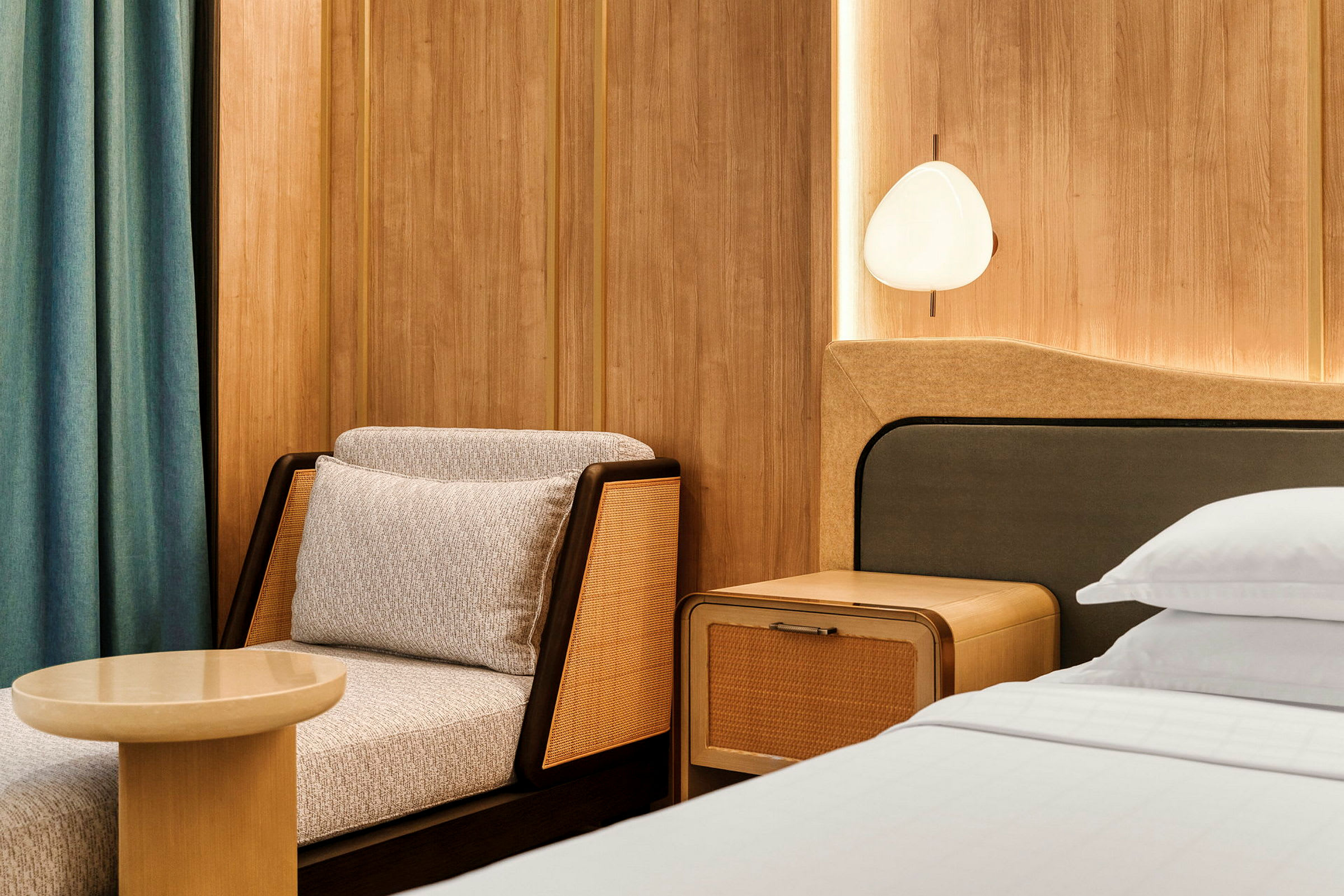 Sittgrupp och en del av en säng i ett modernt hotellrum med träpaneler. (AI-genererad text)