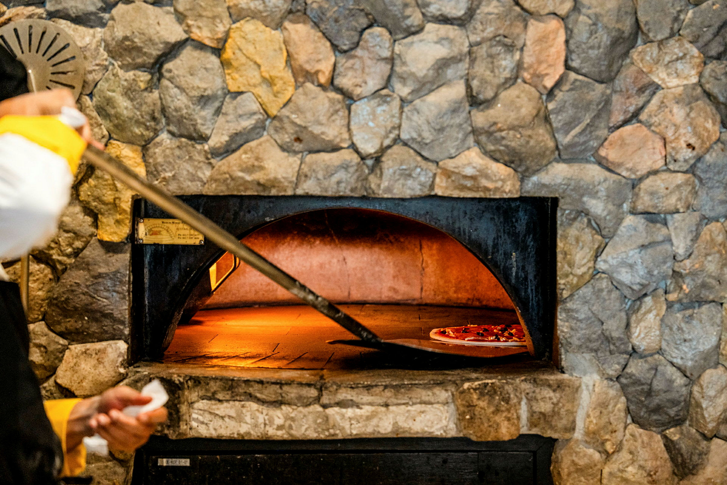 En stenugn med en pizza som gräddas på en bakspade. (AI-genererad text)