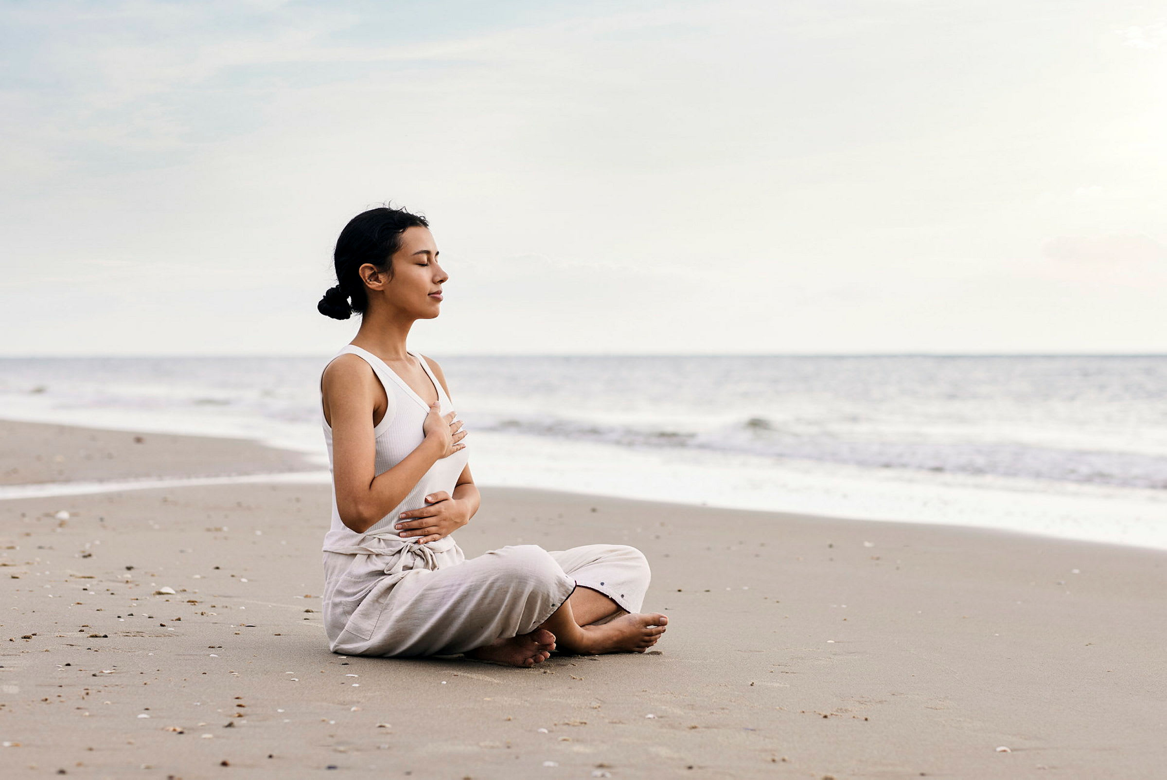 Person sitter på en strand och håller handen på bröstet. (AI-genererad text)