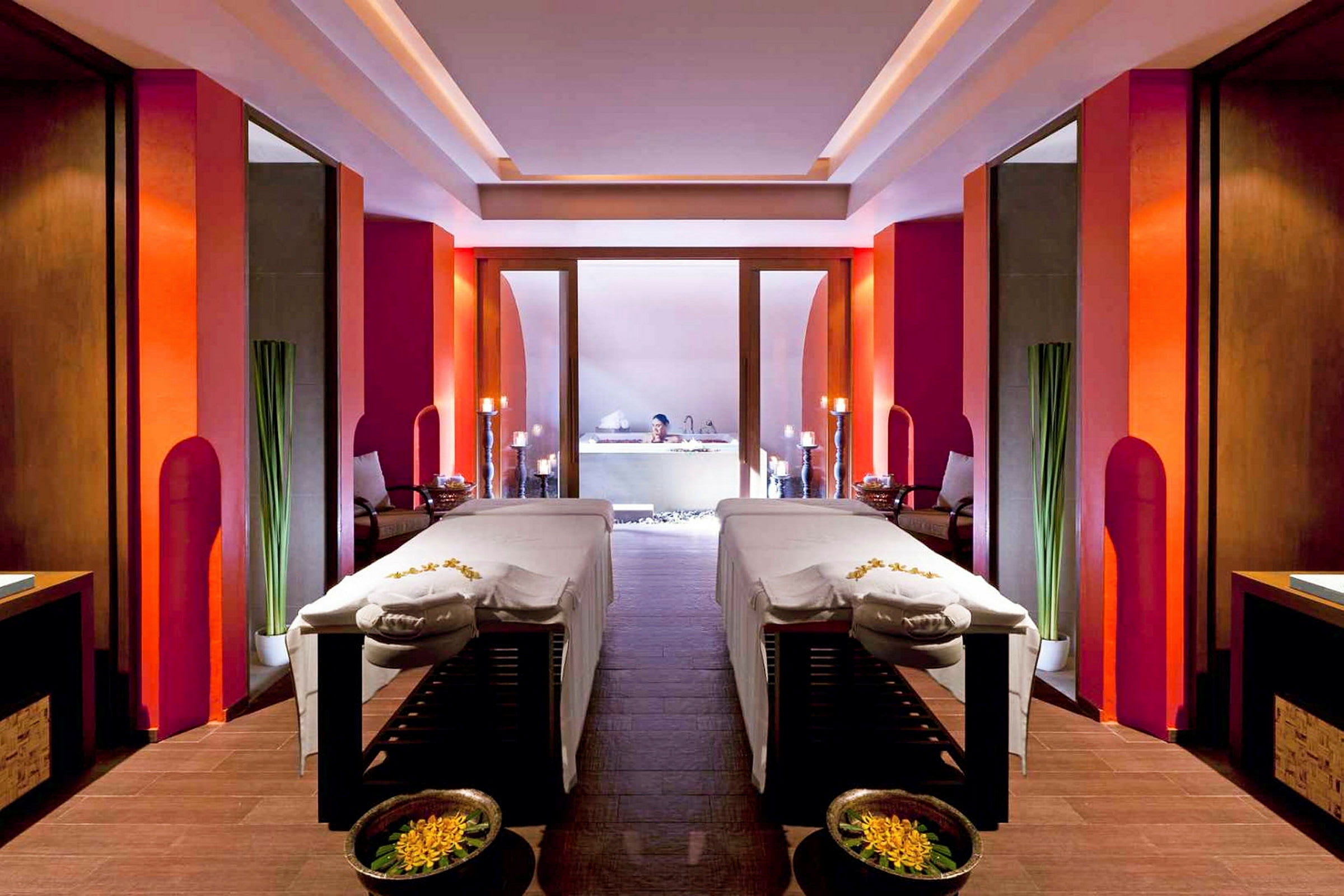Ett spa-rum med två massagebänkar, dekorerat med blommor och omgiven av moderna, varma färgtoner. (AI-genererad text)