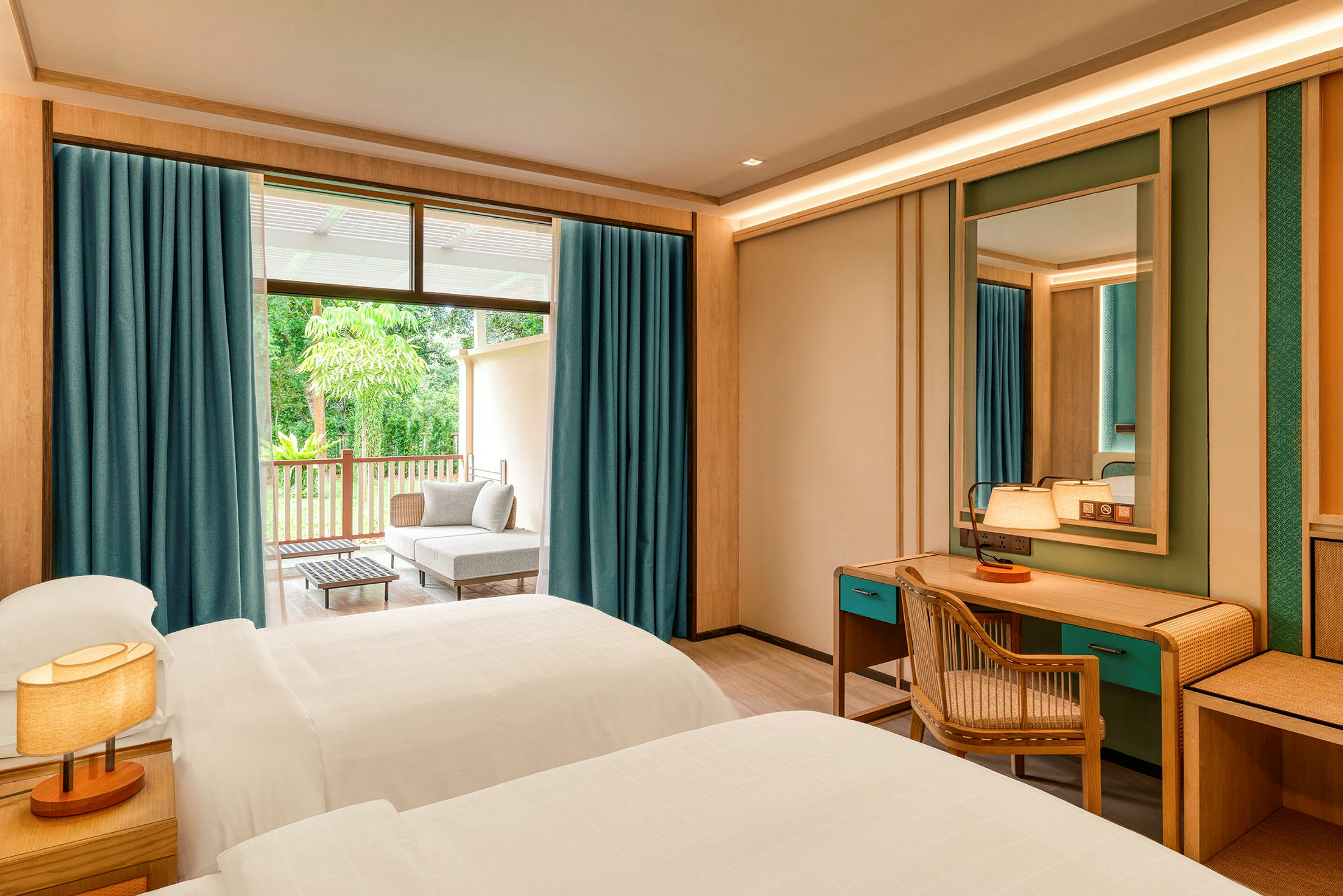 Ett hotellrum med två enkelsängar, ett skrivbord med stol och spegel samt en balkong med sittgrupp utomhus. (AI-genererad text)