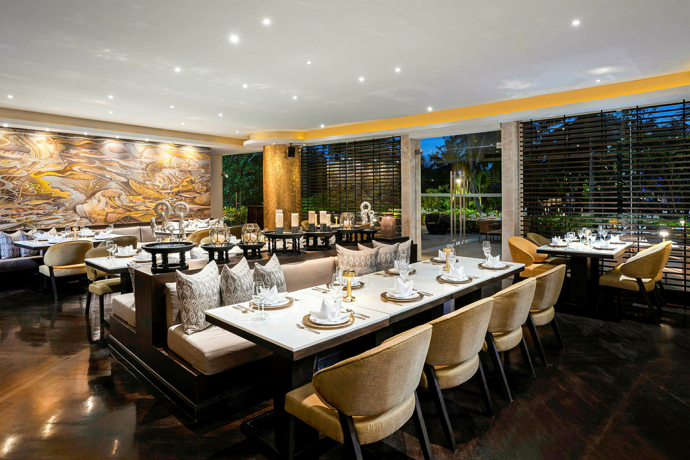 Restaurang med ett elegant och modernt interiör, dukade bord och stolar samt dekorativ konst på väggen. (AI-genererad text)